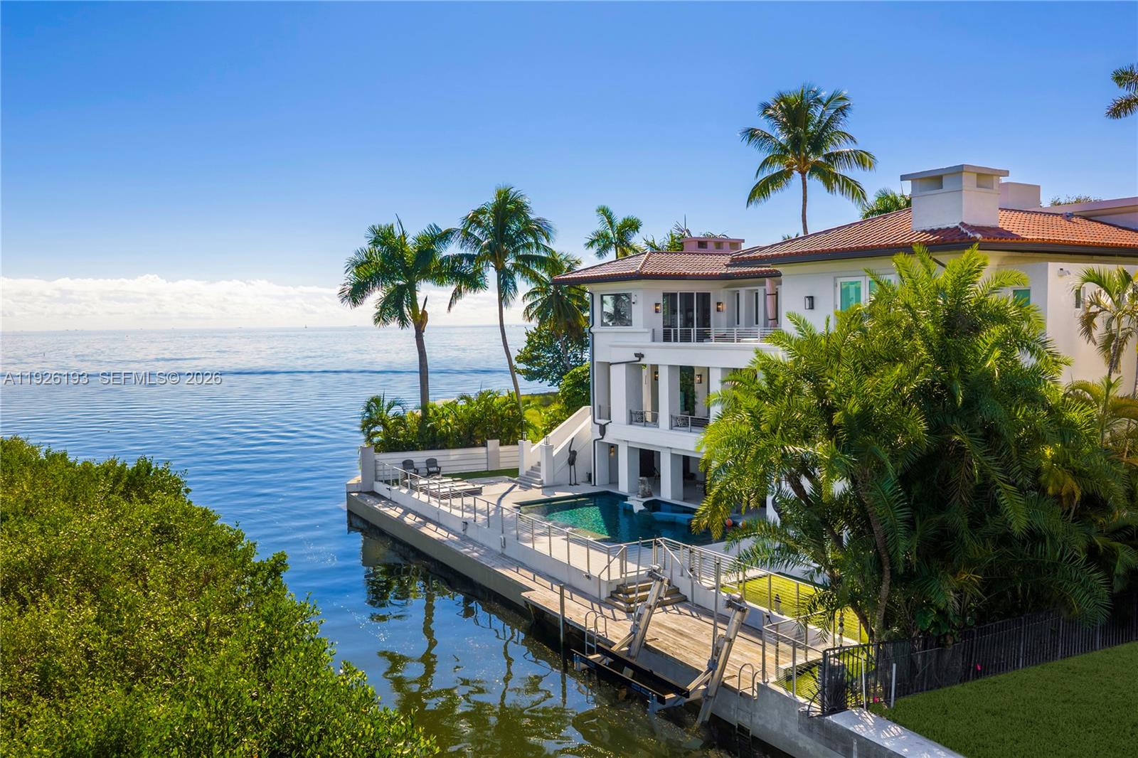 Rarely Available Bayfront Estate! Experience unobstructed Biscayne Bay and Miami skyline views from this gated 3-story residence in the heart of Coconut Grove. Originally designed by Jorge Hernandez, this masterfully reimagined home features multimillion-dollar upgrades and is set on a quiet cul-de-sac with 108’ of protected water frontage and a private dock with boatlift. Inside, a dramatic great room with soaring 25’ ceilings showcases breathtaking water views, complemented by sophisticated living areas featuring 4 gas fireplaces, Calacatta marble floors, and a completely rebuilt chef’s kitchen with new appliances. All bedrooms offer ensuite baths, including a spectacular primary suite with bay views, a spa-style bath featuring an air-jet tub and separate shower, and a newly created expansive custom closet. Designed for effortless entertaining, the home offers a resort-style pool and spa, multiple balconies, covered patios, a summer kitchen, and a rooftop terrace. Additional highlights include a 3rd-floor office with sweeping bay and canal views, a gym overlooking the canal and pool, a 2nd laundry room, impact windows and doors, upgraded security systems, a 3-car garage, and 1 covered carport space in the driveway. Perfectly positioned in one of the Grove’s most coveted bayfront enclaves, moments from top public and private schools including Ransom Everglades, Carrollton, St. Stephen’s, and St. Hugh.