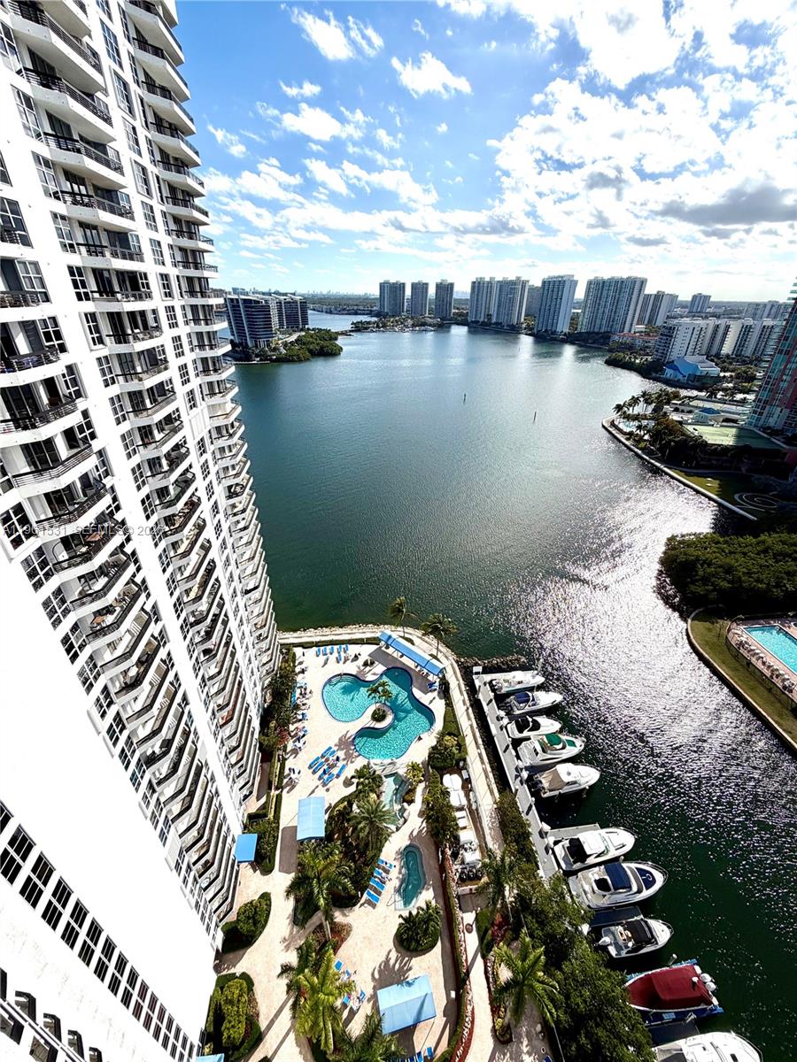 Experience refined luxury and stunning panoramic views in this exceptional 2-bedroom, 2-bathroom corner residence featuring a den and a wrap-around balcony. Located in the highly desirable Mystic Pointe Tower 500, this home offers breathtaking water, city, and golf course views from every room. Residents of Tower 500 enjoy access to premier amenities, including tennis and pickleball courts, a fully equipped gym, fitness classes, a recreation lounge, and a card room. The resort-style pool area with a Jacuzzi is perfect for relaxation, while valet service and five electric vehicle charging stations at the town center provide added convenience. This pet-friendly community welcomes your furry companions. New AC installed in 2023. Schedule your private showing today.