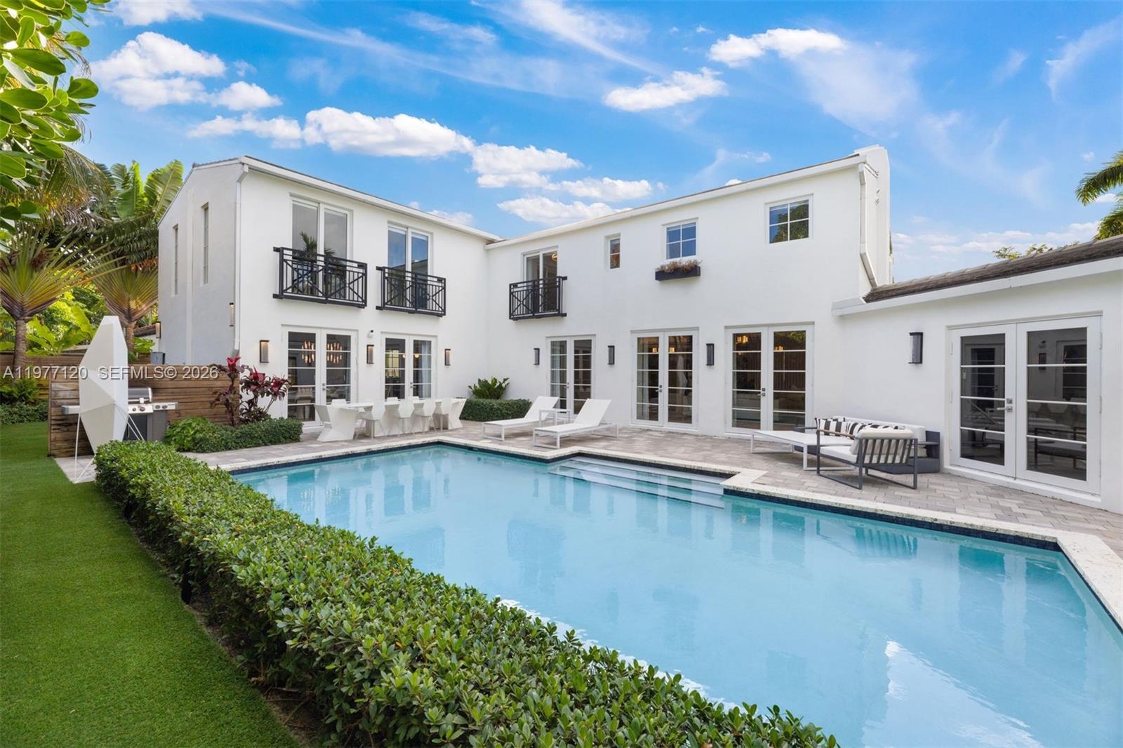 This luxurious Miami Beach estate presents a seamless blend of grandeur and chateau elegance. Privately set behind front hedging, the home welcomes you with a large driveway and an impressive sense of arrival. Offering exceptional privacy and space, the residence features 6 bedrooms and 6.5 bathrooms, each with its own ensuite.
The open-plan kitchen is appointed with high-end finishes and top-of-the-line Wolf, Miele, and Sub-Zero appliances, flowing effortlessly into a spacious dining area and inviting family room. A formal living space, currently used as such, offers flexibility and could easily be transformed into a formal dining room. Just off the kitchen, a full laundry room and dedicated media room add convenience and functionality. The exquisite primary suite serves as a private retreat, complete with a sitting area overlooking the pool and patio. A chic office, which also functions as an ensuite bedroom, adds versatility and convenience. The first-floor guest suite impresses with its own kitchenette, living area, and direct access to the pool and patio, offering beautiful outdoor views. The backyard features an outdoor dining and seating area, and a side yard with room for a playground or garden. Ideally located near upscale dining and shopping, and just moments from the ocean, this residence embodies the ultimate Miami Beach lifestyle.