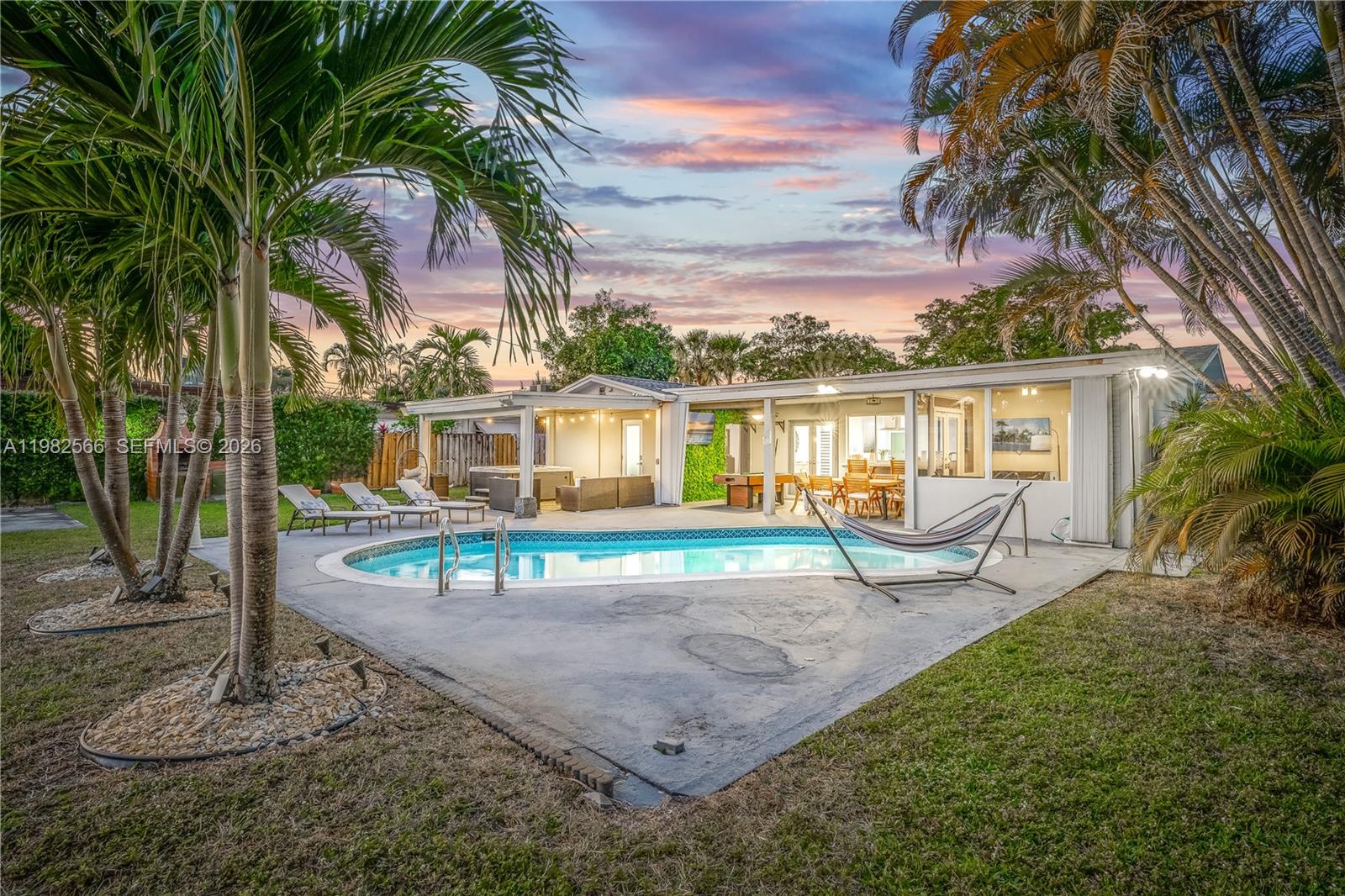 Beautifully renovated 3-bedroom, 2-bathroom pool home in Hollywood Hills situated on a spacious 10,000+ sq ft lot. This bright and modern home features an open layout with elegant porcelain floors, updated kitchen and bathrooms, and abundant natural light throughout. The backyard is a private tropical retreat with a heated pool, hot tub, covered patio, outdoor dining area, and lush palm trees, perfect for entertaining or relaxing. Additional features include CBS construction, hurricane shutters, central A/C, and a large driveway. Conveniently located near parks, shopping, dining, major highways, and just minutes from the beach. A perfect blend of comfort, style, and South Florida lifestyle.