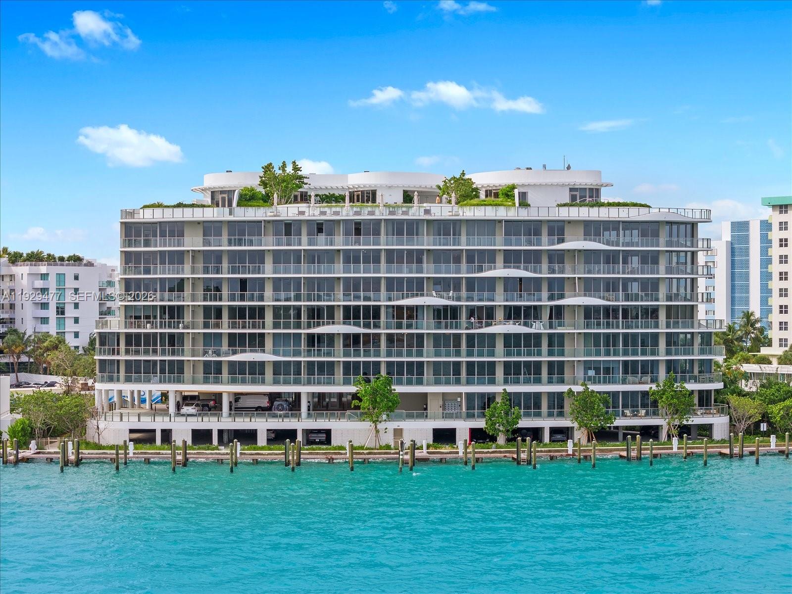 Onda is Bay Harbor Islands’ newest architectural landmark, completed in 2024. This expansive 3-bedroom + Den, 4.5-bathroom condo offers 3,075 square feet of refined interior living space, thoughtfully designed to capture the serenity and beauty of its surroundings while delivering a truly elevated lifestyle. East and west-facing balconies showcase direct-water views, allowing you to enjoy glowing sunrises in the morning and tranquil sunsets in the evening. Floor-to-ceiling glass fills the residence with natural light and creates a seamless indoor-outdoor flow, ideal for both everyday living and entertaining. The Snaidero-designed kitchen blends Italian craftsmanship with modern functionality, featuring sleek custom cabinetry and a full suite of Miele appliances. Open living and dining areas are complemented by clean architectural lines and sophisticated finishes throughout. Each bedroom offers generous proportions and en-suite bathrooms with spa-inspired details, while the additional powder room provides convenience for guests. Located in the heart of Bay Harbor Islands, Onda offers a boutique island lifestyle defined by walkability, waterfront beauty and a sense of privacy. Just moments from Bal Harbour Shops, pristine beaches, fine dining and top schools, this residence delivers the perfect balance of tranquility and connectivity. A rare opportunity to own a modern waterfront home in one of Miami’s most desirable island communities.