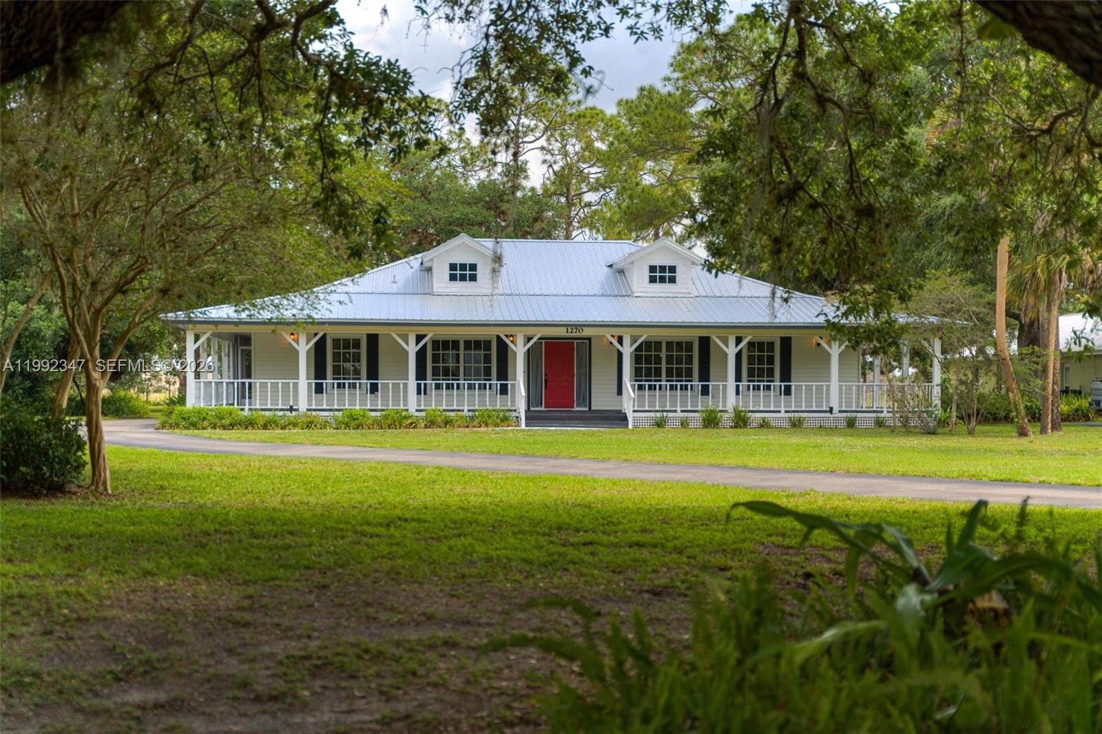 Spectacular Old Florida–Style Home in Prestigious Riverbend! Nestled on .89 acres beneath majestic Old Florida oak trees, this beautiful home offers classic charm combined with modern updates. A welcoming wraparound porch spanning two sides of the home invites you to relax and enjoy the peaceful, natural surroundings. French doors open directly to the screened rear lanai, creating a perfect indoor-outdoor connection.  Between the garage and den is a second screened porch with 1,ooo square feet, a wonderful spot for nature lovers to relax and enjoy the surrounding landscape and low-maintenance xeriscaping. The oversized garage accommodates up to four vehicles and still provides ample space for a workshop or additional storage. Located within Riverbend, an exclusive gated community of just 44 homesites, residents enjoy a private road, double security gates, and community utilities including sewer, water, and irrigation water. The Riverbend community, is located at the end of a quiet road, surrounded by water management lands and ranch acreage, allowing residents to experience nature, privacy, and Old Florida beauty at its finest.