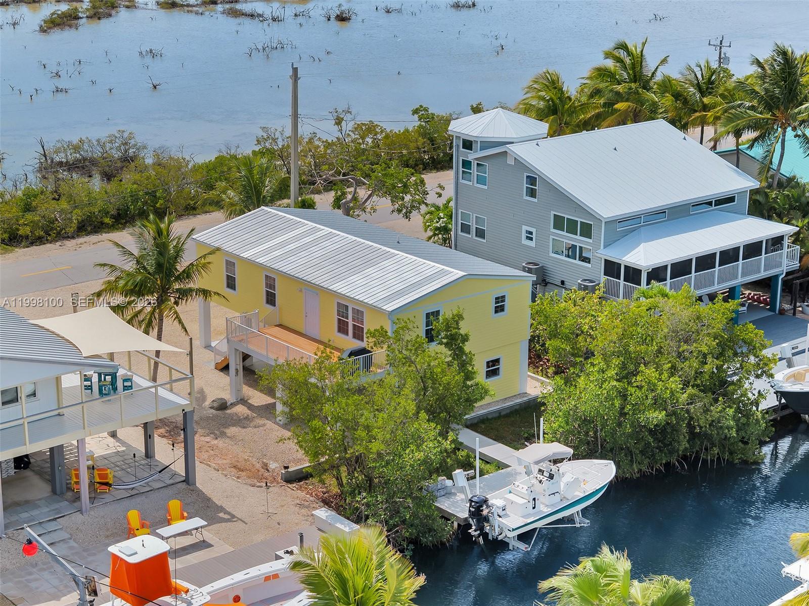 Offered in the highly sought-after Jolly Roger Estates, this beautifully maintained, one-owner canal-front home is just 11 years old and truly move-in ready. Elevated and thoughtfully designed, the 1,296 sq. ft. residence offers three bedrooms and two bathrooms, enhanced by refined finishes including crown molding, tray ceilings, tile showers, and a bright, open-concept living space ideal for coastal living. Built for both comfort and peace of mind, the home features a metal roof installed in 2018 along with impact-rated windows and doors throughout. Enjoy added privacy and nightly sunset views over the protected salt marsh directly across the street—an unspoiled natural backdrop that will never be developed. Boaters will appreciate the free-flowing, clear-water canal with excellent access to both the ocean and the bay. The private dock with a 7,000-lb side-lift boat elevator makes heading out for fishing, diving, or sunset cruises effortless. The spacious lot offers a large driveway, double covered parking, and ample room for boat trailers and additional vehicles. Downstairs, a full concrete pad and enclosed angler's room provide the perfect space for storing fishing gear, dive equipment, and all your island toys. Located near mile marker 28.5, Jolly Roger Estates is a peaceful, palm-lined waterfront community on the Atlantic side of Little Torch Key, offering direct access to Pine Channel and world-class boating, fishing, and diving at nearby Looe Key Reef.