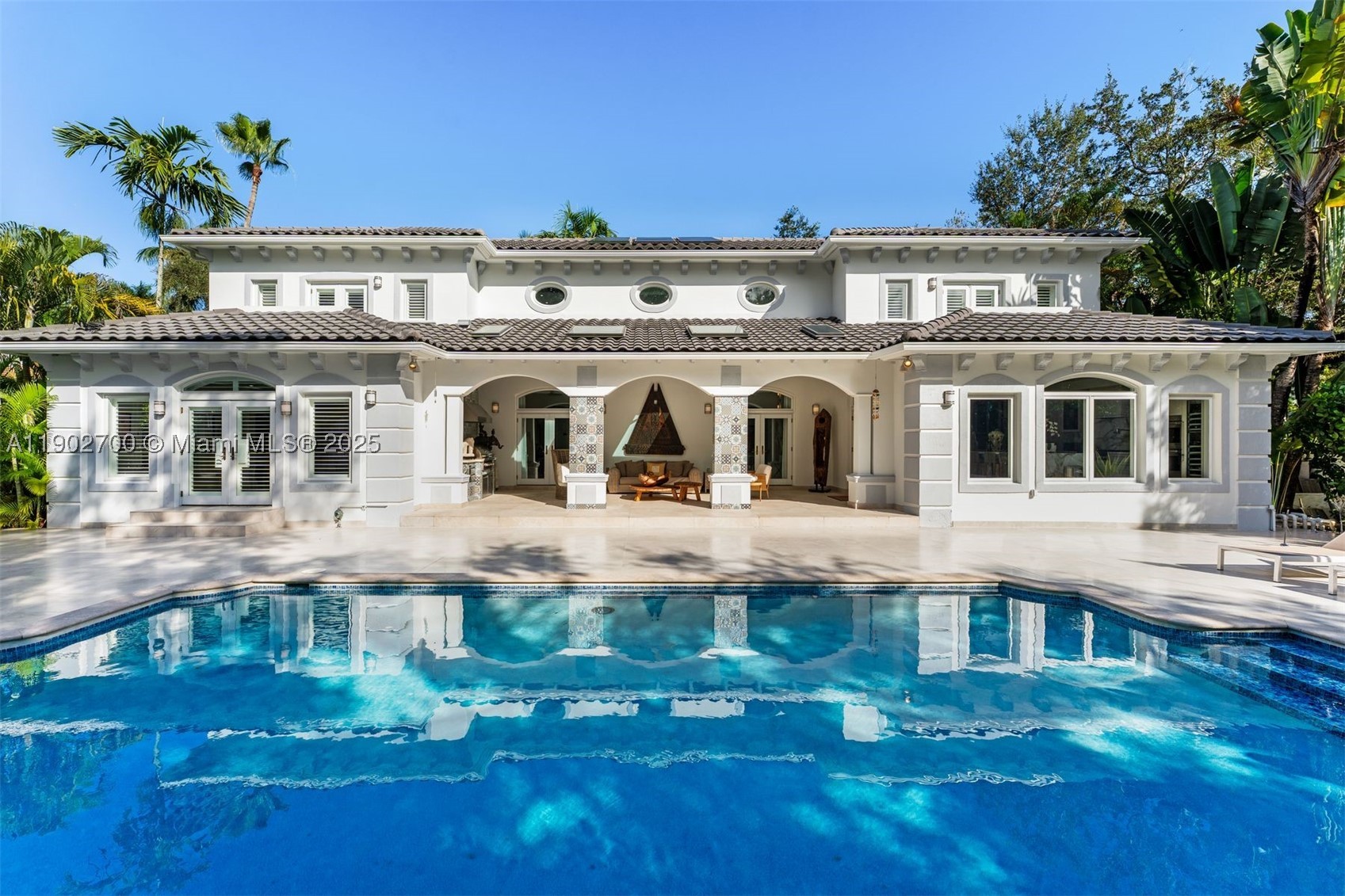 Situated in the gated Palms Estates of North Pinecrest, this remodeled residence sits privately on a cul-de-sac and offers 5 bedrooms, 5.5 baths, including separate guest quarters. A grand entry with vaulted ceilings opens to bright, spacious living areas filled with natural light. Upgrades from 2021–2022 include full interior and exterior repaint, new kitchen cabinets, new AC units, upgraded doors, custom pergola, renovated pool area with new flooring, all bedroom closets replaced, cactus garden, new outdoor lighting, security cameras, dimmers, sound system, and new interior flooring. The Scavolini gourmet kitchen overlooks the pool, while the primary suite features a private lounge or office with direct pool access. Outdoor areas are ideal for entertaining or relaxing in privacy.