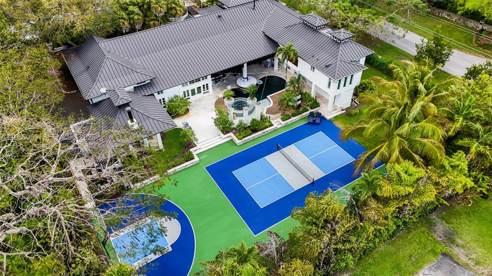Welcome to one of Pinecrest’s most distinguished estates! Nestled on a sprawling corner lot framed by majestic oaks and vibrant fruit trees, this custom-built masterpiece spans over 11,000 total SF of pure architectural excellence. The 6BR/5.5BA floor plan is a study in refined luxury, featuring soaring ceilings, elegant millwork, & timeless finishes. Beyond the home office, gym & private wine cellar, discover a whimsical touch of genius: a handcrafted wooden slide connecting two expansive family rooms—an unforgettable detail for the young at heart! The interior flows seamlessly to a resort-style oasis, where a custom pool, professional pickleball court & summer kitchen are enveloped by lush tropical landscaping. This is more than a home; it is the ultimate expression of Pinecrest living!