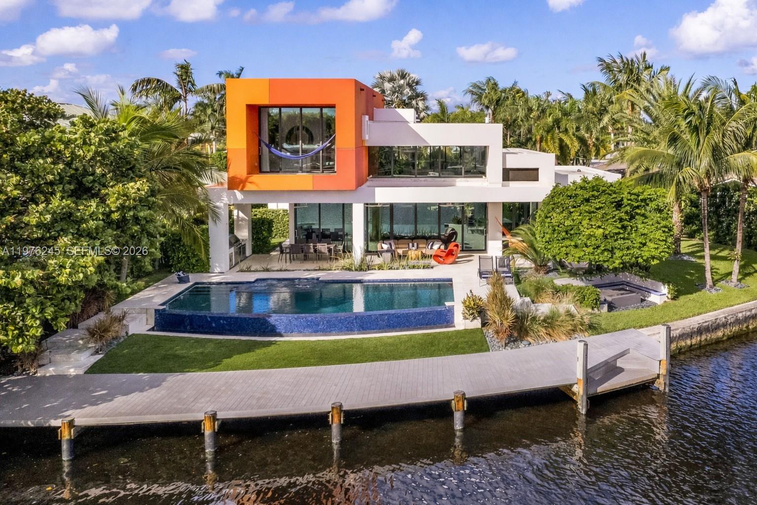 Discover an architectural showpiece where Modernist design meets tropical elegance in Wilton Manors, East Fort Lauderdale. Designed by SH Brandt & Associates, this striking residence blends visionary architecture with refined craftsmanship. Spanning more than 3,420 square feet, the pavilion-inspired layout features sliding volumes that blur the boundary between indoor and outdoor living. Expansive interiors open to a breathtaking waterfront setting with an infinity-edge pool overlooking the South Fork of the Middle River and a sunken fire pit perfect for entertaining. The home offers 130 feet of waterfront with two private docks and a boat lift, providing easy access for boating enthusiasts. Lush tropical landscaping including Dwarf Fountain Grass, Bromeliads, and a dramatic Dragon Tree creates a secluded oasis. Inside, polished limestone floors transition seamlessly to the reef limestone pool deck. A dramatic floating staircase by Indiana artist Tim Schmidt—crafted with tempered glass railings and reclaimed white oak from a centuries-old barn anchors the interior, while a salvaged neon sign from New York’s historic Beaumont Hotel adds vintage character. The chef’s kitchen features a 48” Wolf gas range, integrated Sub-Zero refrigerator, and a 150-bottle Thermador wine cooler, paired with Morantz custom cabinetry and Krion countertops by Porcelanosa. Located just 2.5 miles from the beach in walkable Wilton Manors, this special home captures the best of South Florida living.