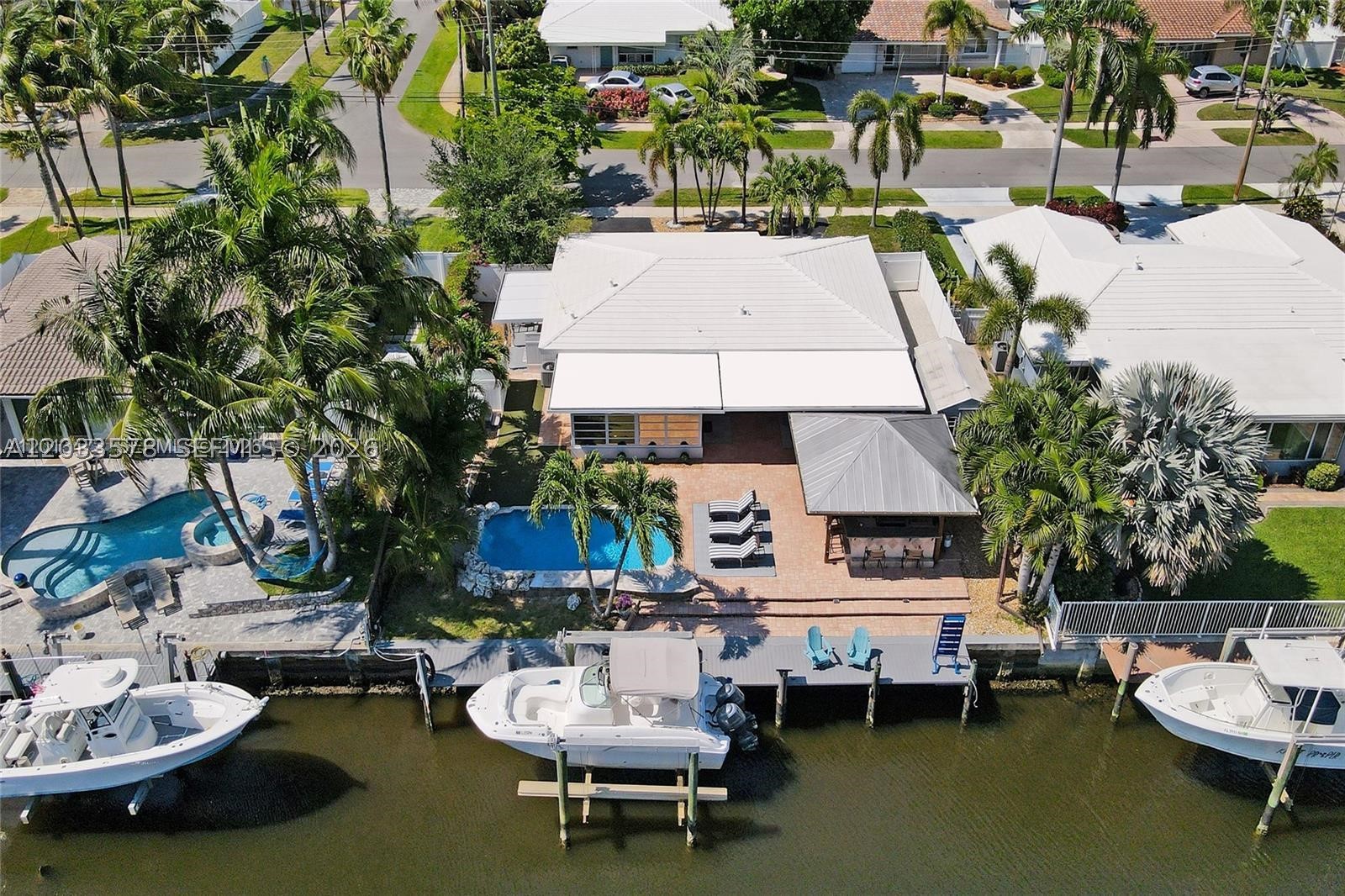 The Ultimate Boater's Oasis in Garden Isles–Waterfront Luxury Re-imagined. Rare double-wide canal making navigation a breeze. Enjoy direct ocean access just minutes from the open ocean and unique gated parking area for RV or other toys. RARE 75 ft water frontage and upgraded boat lift. Only 2 fixed bridges w/ high clearance on a quiet, no-thru traffic street perfect for children, grandchildren & dog walking, this remodeled 3-bed 2-bath Smart Home offers the perfect blend of tropical relaxation and high-tech convenience (Smart features include Voice-operated or by cell phone> door locks, ceiling fans, lighting, appliances & thermostat. Entertainer's dream w/ outdoor tiki bar w/ metal roof and professional-grade outdoor kitchen w/ running water. Whether you’re hosting a summer BBQ or practicing your short game on the custom putting green surrounding the pool, the outdoor lifestyle here is unmatched. After sunset, unwind in the 5-person hot tub or find peace in the lush reading garden filled with blooming roses. Features a rare 32x12 ft gated side area perfect for boat trailer RV, golf cart fleet, or additional car storage, 14x8 ft shed for your tools and addt'l storage, IMPACT windows, composite dock decking, new flooring and bathrooms. Manatee, tarpon, blue crab & many saltwater fish live in canal. Sit back and fish or watch ocean life visit your dock daily. More than a home; it’s the waterfront lifestyle you’ve been waiting for. See Supplemental Remarks for further details.