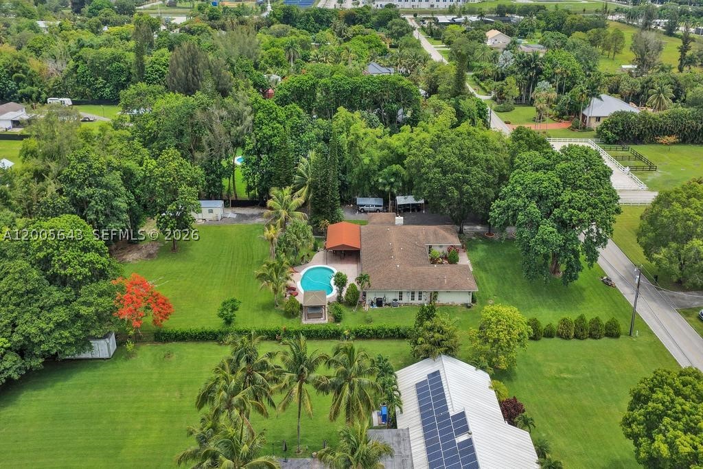 This elegant remodeled, four-bedroom, three-bath home sits on over an acre and offers comfort and style. The spacious family room has huge picture windows overlooking a large private fenced backyard with a freeform pool, two pergolas, outdoor speakers, misters, and an 800-square-foot covered patio—ideal for entertaining. Relax in the jacuzzi under the stars or enjoy the butterfly garden at the entryway. The modern 2 tone, white & gray kitchen features double pantry, shaker cabinets, quartz countertops, premium appliances, and a window overlooking the  backyard. Inside, there are 4 bedrooms, 2 are ensuites, nicely updated/remodeled baths all with glass shower doors. Dual air conditioning units, porcelain flooring throughout, a fireplace, French doors, and fiber optic internet. The laundry room has new washer/dryer and a laundry tub, and provides access to the air-conditioned, tiled garage with impact door. (506 SF, SWEET!)  Special upgrades include a whole-house water filtration system, new pool equipment, a new 30X12 paneled, insulated shed with AC and dehumidifier, an adjacent carport and an extra 180 sf building with air conditioning and French doors that serves as an office or studio, while the 10-year-new roof and impact windows offer peace of mind. 300 ft long double wide driveway can fit all of your toys! Located in an equestrian neighborhood with A-rated schools, this property is ready for you and your horses, RVs, boats, trailers, jetski's!