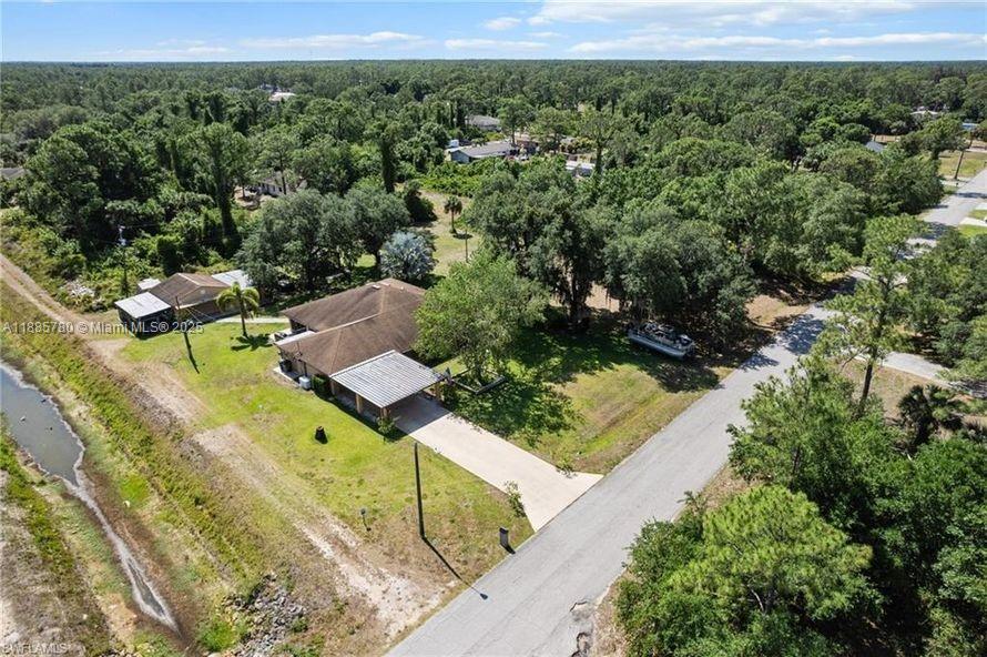 Welcome to your private paradise—this beautifully maintained 4-bedroom, 3-bathroom home sits on nearly 2 acres of serene, high-and-dry land with no flood zone designation. Two of the bedrooms are full a suite, offering added comfort and flexibility. Designed for both everyday living and entertaining, the home features an open floor plan in the family area, a separate living room, and an expansive lanai perfect for relaxing while enjoying the peaceful sounds of nature and the vibrant birdlife. Spacious layout and picturesque setting. Parking and storage are no issue with an 8-car driveway, 2-car attached garage, and fenced-in vehicle storage, along with two fully powered workshops—offering space for up to 10 vehicles.