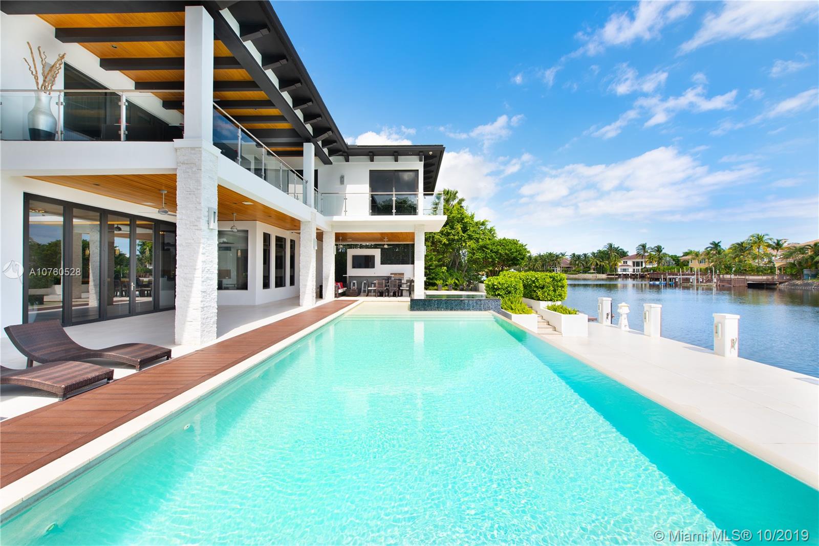 On November 25th, this modern waterfront estate with 150 feet of dockable frontage will be sold at Luxury AUCTION® WITHOUT RESERVE! List price used here is for REFERENCE ONLY. Offered in cooperation with Platinum Luxury Auctions. Inquire for complete Auction details. Featuring contemporary touches from stone accents to floating stairs, spacious entertaining areas including several lounges, an open-plan formal dining room, and an exceptional bar room with all that's needed for a full-blown bash. A gourmet kitchen with Viking and Miele appliances opens to a well-appointed outdoor dining area overlooking the water. A manicured rear lawn complements the infinity pool and spillover spa, showcasing native plantings, a fire pit, & a view stretching to the oceanfront towers on Hollywood Beach.