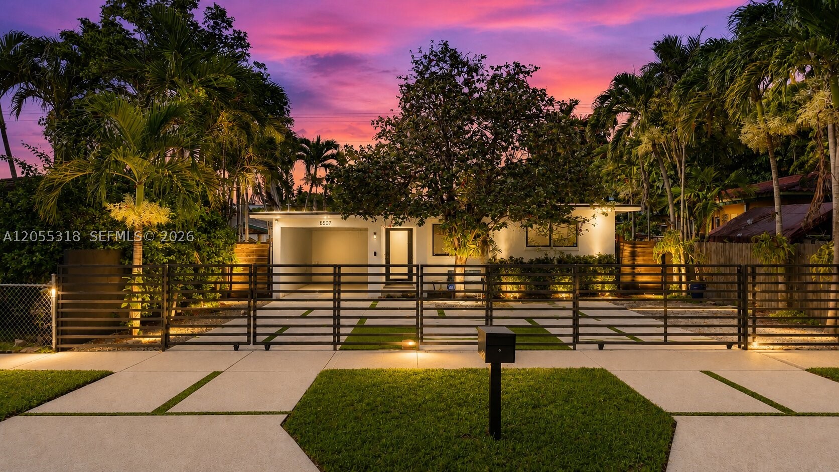 Tucked behind a private rolling gate on a lush, palm-lined street, this fully renovated mid-century home delivers the feel of a gated compound in one of Miami's fastest-appreciating pockets between Coral Gables and Bird Road. The curb appeal is unmatched: an architectural grid of oversized concrete pavers and turf ribbons, custom horizontal-slat metal fencing, designer landscape lighting, and a covered carport — a front yard that photographs like a boutique hotel.
Inside, original polished terrazzo floors flow through a bright, open layout. The chef's kitchen features quartz countertops, white shaker cabinetry, a Calacatta marble backsplash, and stainless steel appliances, opening to a spacious dining room with breakfast bar. The showpiece is the expansive glass-wrapped Florida room with vaulted whitewashed beam ceilings — a true second living space perfect for entertaining, lounging, or working from home with garden views on three sides.
Two comfortable bedrooms and a fully remodeled bath with marble-clad walls, frameless glass shower, and matte black fixtures. A large utility room off the carport adds laundry, storage, and workshop space rarely found at this price point.
Out back: a fully fenced, ultra-private yard with sprawling lawn, paver patio, and storage shed — room for a pool. Minutes to Coral Gables, South Miami, UM, MIA, and Bird Road dining. No HOA. Move-in ready — nothing to do but unpack.