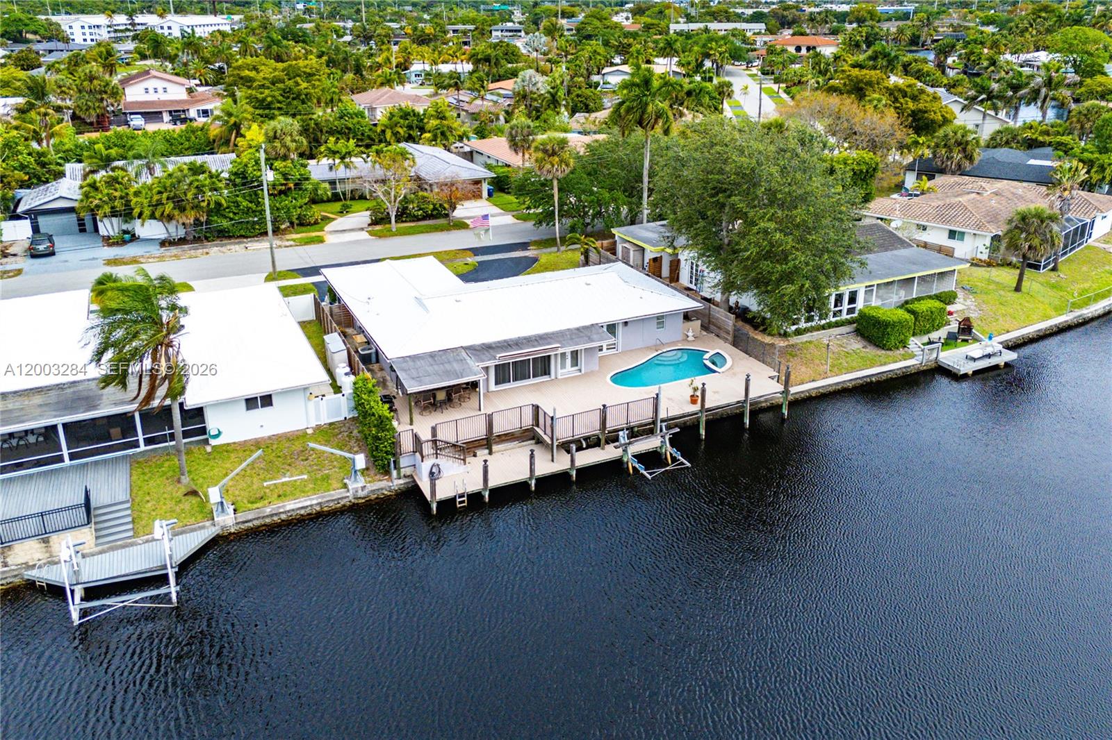 Welcome to waterfront living in the sought-after Jenada Isles community in Wilton Manors! This 1,876 square foot 3-bedroom, 3-bath residence has a thoughtful layout offering an excellent indoor-outdoor flow. The sparkling pool, covered patio, private dock, and boat lift create the ultimate setup for boating, relaxing, and entertaining right in your own backyard.  Additional highlights include a durable metal roof, hurricane shutters for peace of mind, and a spacious 2-car garage providing ample parking and storage. Perfectly situated minutes from downtown Fort Lauderdale, Wilton Dr, Fort Lauderdale Beach, Major highways, and International Airports.