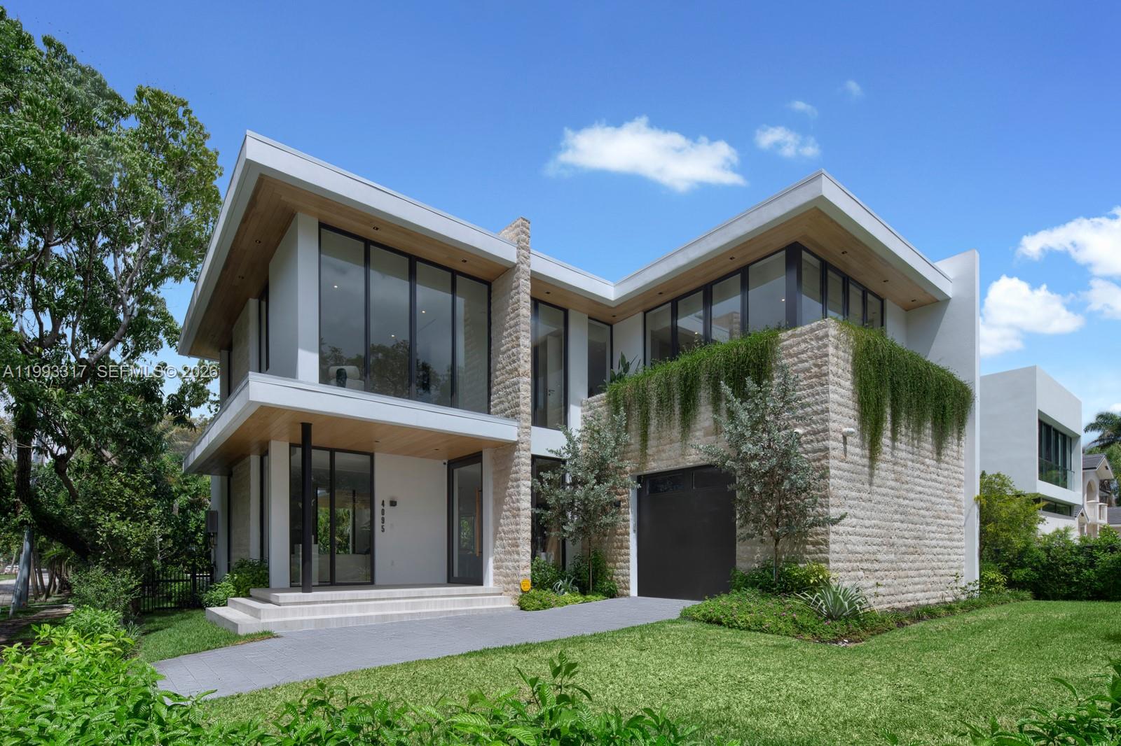 Villa Serene, a modern sanctuary in one of Coconut Grove’s most coveted tree-lined enclaves, steps from Merrie Christmas Park. Designed by Ramon Pacheco, built by The Calta Group, and curated by Assure Interiors. This smart home features 5 bedrooms, 5 full baths, and 2 half baths with a cabana bath, designed for seamless style, luxury, and comfort. Interiors feature porcelain floors in main living areas, warm hardwood upstairs, and custom Italian doors throughout, creating a serene and sophisticated atmosphere. The open kitchen by Mia Cucina is anchored by a waterfall island with Cosentino porcelain surfaces and Sub-Zero and Wolf appliances, including a gas cooktop and convection steam oven, perfect for culinary creativity and entertaining. Fully retractable glass doors connect the living spaces to a private landscaped backyard with a pool, covered terrace, and fully equipped summer kitchen, great for year-round gatherings. Additional highlights include Savant smart home integration, a security system, and dual-zone A/C. Ideally located near Coconut Grove Village with dining, shopping, marinas, parks, and top-rated schools. Sophisticated design for a luxurious lifestyle with elegant indoor-outdoor living!