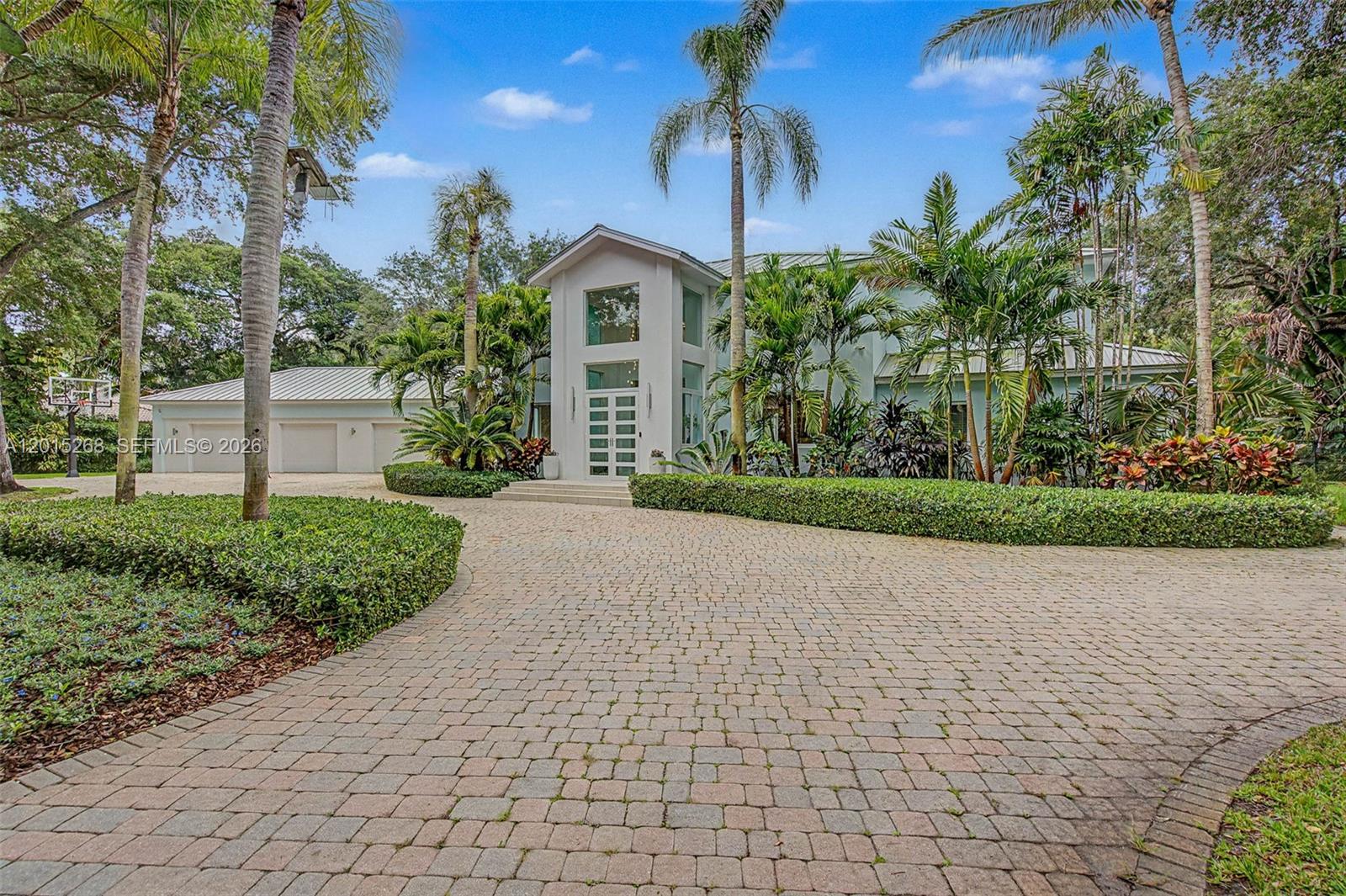 Ideally set in northeast Pinecrest, this 5-bedroom, 7-bathroom residence offers a rare combination of privacy, natural beauty, and effortless indoor-outdoor living. A fully fenced and gated property set beneath mature oak trees and lush foliage, the home opens to a south-facing backyard that maximizes natural light over the pool year-round.

The open floor plan connects the kitchen seamlessly to the Florida room and family room, with glass sliders spanning the rear of the home and opening directly to the pool and expansive outdoor entertaining spaces. Grassy lawns frame the private backyard, creating a resort-quality retreat at home.

Above, the primary suite commands a large private balcony, complemented by two separate bathrooms and two separate closets. Natural light pours throughout the residence. All impact windows and doors. Fully fenced yard with gated entry.

A property defined by position, privacy, and light in one of Pinecrest's most sought-after locations.