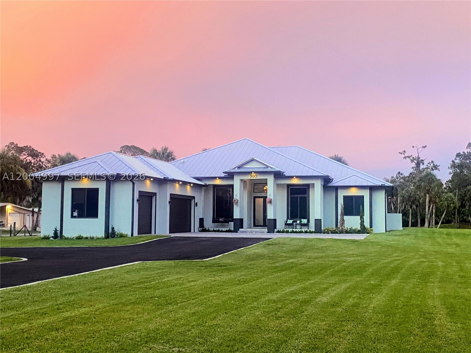 Welcome to this custom-built masterpiece offering a total of 4,585 square feet on 100% upland acres in Golden Gate Estates with NO HOA, NO CDD fees, and NO flood insurance required (Zoned X500).  Free of borrow pits, this expansive property affords maximum usability of it's 2.5 acres.  Designed to last, the home features solid stem-wall construction, a premium standing-seam metal roof, impact-rated windows and doors, and a whole-house reverse osmosis system.  The grand interior showcases soaring 13-foot coffered and double-tray ceilings, designer light fixtures, and seamless Italian wood-look porcelain tile flooring.  At the heart of the home is a chef’s kitchen featuring premium Calacatta quartz countertops, a breakfast nook and a wet bar.  The primary wing serves as a private sanctuary complete with a spa-inspired en-suite and dual walk-in closets.  On the opposite side of the home you have three spacious guest suites.  One with an en-suite and two connected by a thoughtful Jack and Jill bathroom with its own separate entrance making it suitable for multi-generational living.  The indoor living spaces flow out to an expansive, screened-in lanai. Relax in the 7 person spa or enjoy the year-round breeze surrounded by a beautifully manicured Floratam lawn.  In the evenings, unwind on the front porch to take in breathtaking Florida sunsets.  Complete with an oversized 3-car insulated garage and EV charging outlet, this custom estate is a rare find.
