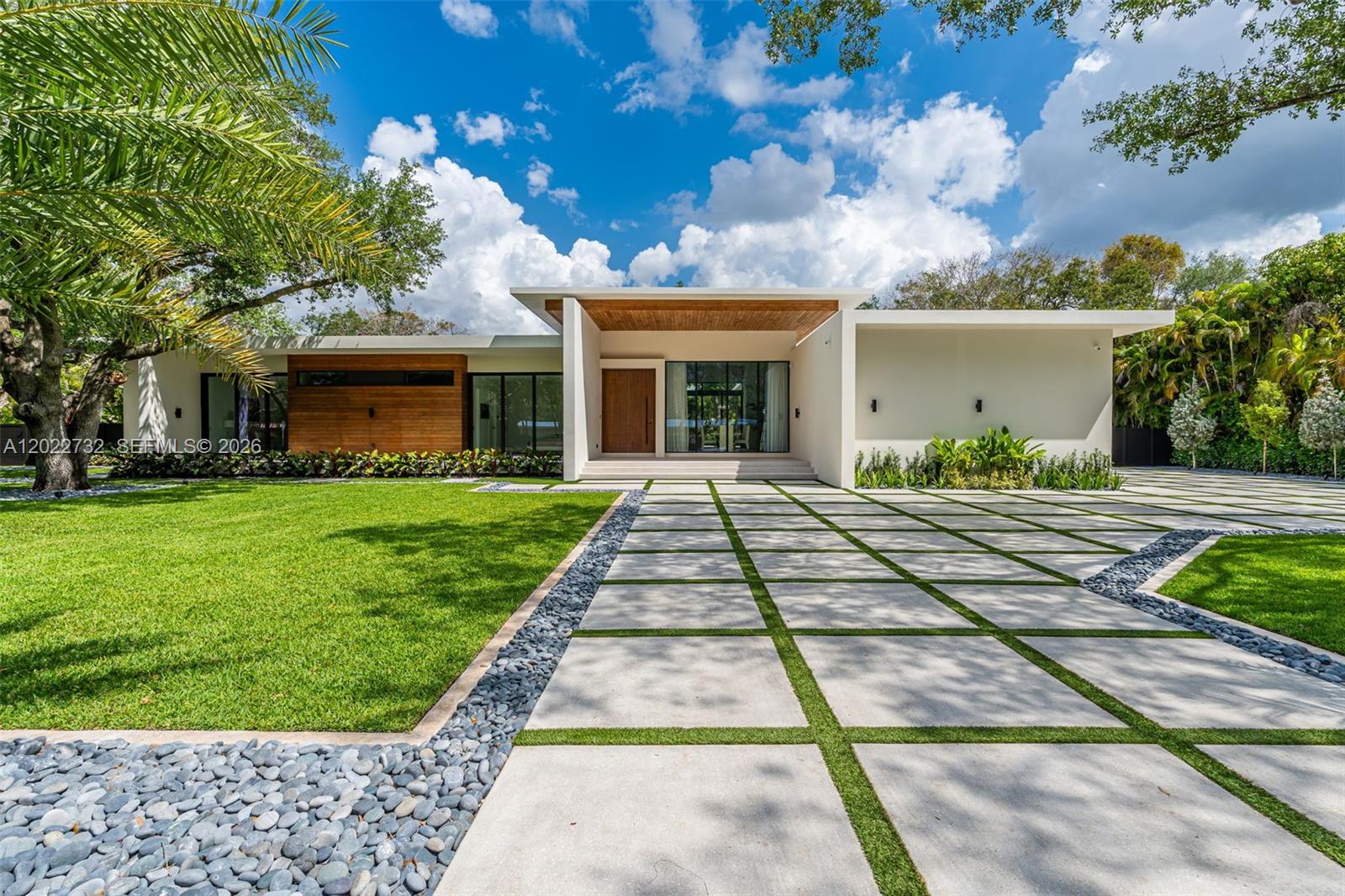 Built with exceptional durability and craftsmanship, this impressive residence offers 8,293 total square feet of solid concrete construction, including 5,349 square feet under A/C. Designed for both comfort and functionality, the home features 6 spacious bedrooms and 6.5 bathrooms, highlighted by a seamlessly incorporated 1-bedroom, 1-bath detached guest house complete with dual walk-in closets. A striking 11-foot hurricane-impact mahogany pivot entry door welcomes you into expansive interiors showcasing soaring ceilings, abundant natural light, impact windows and doors, and refined finishes throughout. The gourmet kitchen is thoughtfully designed with premium Italian cabinetry, quartz countertops, and top-tier built-in appliances. Every ensuite bedroom enjoys serene views and direct access to the pool or outdoor living spaces. The luxurious primary suite elevates everyday living with a theater-quality 4K projector and oversized screen, creating a private cinematic retreat. Fully integrated smart home technology enhances convenience throughout.