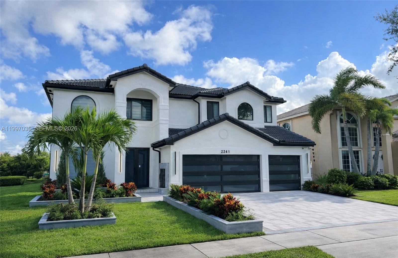A statement in modern architecture, this stunning Miramar Estate was designed for those who expect more. 
From the moment you arrive, the striking modern façade and expansive driveway set the tone for what awaits inside. Clean architectural lines, a three-car garage, and curated landscaping create a bold yet refined first impression. Inside, soaring ceilings and oversized porcelain flooring immediately open the space, reflecting natural light throughout the home. The floating glass staircase becomes a centerpiece both functional and sculptural anchoring the main living area with a sleek, contemporary edge. The kitchen is designed for both everyday living and elevated entertaining. Featuring custom cabinetry, integrated appliances, double wall ovens, and designer hardware, it offers a seamless blend of style and functionality. The oversized island invites gathering, while illuminated display cabinetry adds warmth and sophistication. An enclosed summer kitchen extends your living space, creating the perfect indoor-outdoor flow for entertaining year-round. Just beyond, the pool and deck overlook tranquil lake views offering privacy, serenity, and the ideal backdrop for both quiet mornings and sunset evenings.

This home was designed for those who appreciate detail, space, and the experience of living well.