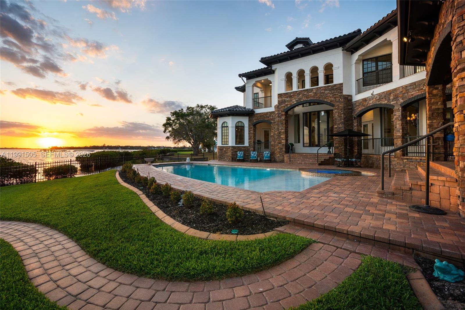 Over 9,000 square feet of fully furnished waterfront living awaits in this exceptional Gulf-access estate in Palmetto, set on over half an acre with deep, navigable water, a private dock, and a 13,000-lb boat lift with direct access to Tampa Bay and the Gulf of Mexico for boating, waterfront dining, and sunset cruises. This high-and-dry residence has never experienced storm water intrusion and includes transferable flood insurance under $5,000 per year. Inside, refined coastal design spans expansive living areas offered turnkey furnished with a few exclusions, anchored by a chef’s kitchen with Sub-Zero refrigeration, Wolf gas cooking with double ovens, dual Miele dishwashers, built-in coffee system, warming drawer, prep sink, and ice maker. Indoor-outdoor living opens to a resort-style pool and spa, outdoor kitchen with premium grill, fire features, and panoramic water views. Additional features include a temperature-controlled wine cellar, billiards and bar room, private theater, exercise room, office, elevator access, en-suite bedrooms, and a main-level primary suite with spa-like comfort and direct outdoor access. Modern upgrades include two laundry rooms, smart-home features, whole-home audio, central vacuum, solar-assisted water heaters, enhanced security, a Tesla EV charger, and a new tile roof completed in 2025, all just minutes from marinas, dining, parks, and downtown Bradenton.