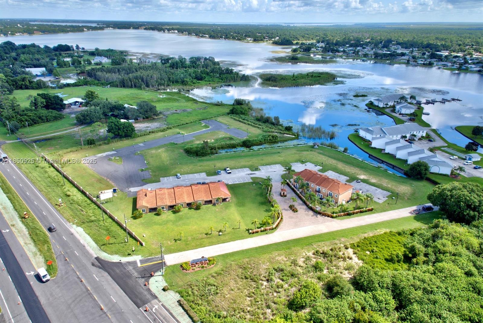 6.05-acre waterfront property on Lake Grassy with frontage on Highway 27. Includes a 9-unit complex built in 2008: five single-story (2 beds, 2 baths) and four two-story units (3 beds, 2.5 baths). Fully paved roads, utilities, and a valid wastewater permit through 2029 make this a shovel-ready project. Approved plans for 42 additional 3-bed, 2.5-bath units (approx. 1,565 sq. ft.) can be adapted to suit your vision. Also features space for a community pool. Existing income-producing units, highway visibility, and water access make it an ideal turnkey opportunity for developers or investors