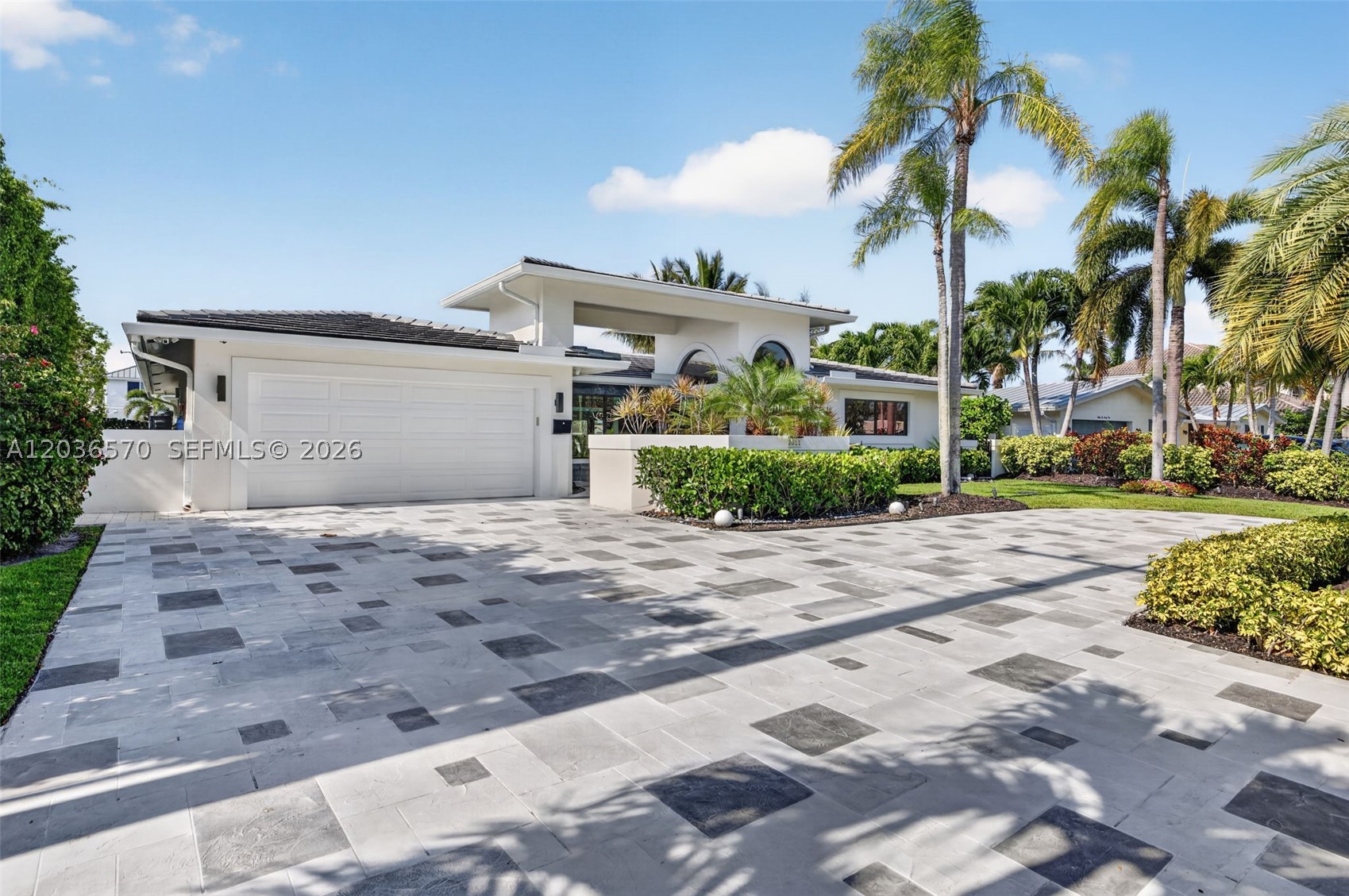 Completely reimagined waterfront residence on Lighthouse Point's coveted South Grand Canal, offering one of the most spectacular long water views in the neighborhood. Thoughtfully renovated with designer finishes throughout, this open-concept home seamlessly blends luxury, comfort, and the ultimate boating lifestyle. Expansive floor-to-ceiling glass showcases breathtaking 180-degree water views and fills the living spaces with natural light. The chef's kitchen features waterfall quartz countertops, custom cabinetry, premium appliances, and an oversized island designed for entertaining. The luxurious primary suite offers a spa-inspired bathroom with dual vanities, a freestanding soaking tub, and an oversized glass-enclosed shower. Step outside to your private waterfront retreat featuring a recently remodeled pool with a sun shelf, waterfall feature, new tile, and Diamond Brite finish, along with two pergolas equipped with electric hurricane shades and a fully outfitted outdoor kitchen. The 2024 composite dock offers water, electric, and a 15,000-pound boat lift, with 90 feet of waterfront, no fixed bridges, and quick ocean access. Additional upgrades include a 2013 roof, whole-house generator with a buried 500-gallon propane tank, double water filtration system, tankless water heater, PVC plumbing, impact windows and doors, 2021 A/C, epoxy-finished garage with mini-split A/C, and a new circular driveway. Designed for those who appreciate exceptional waterfront living!