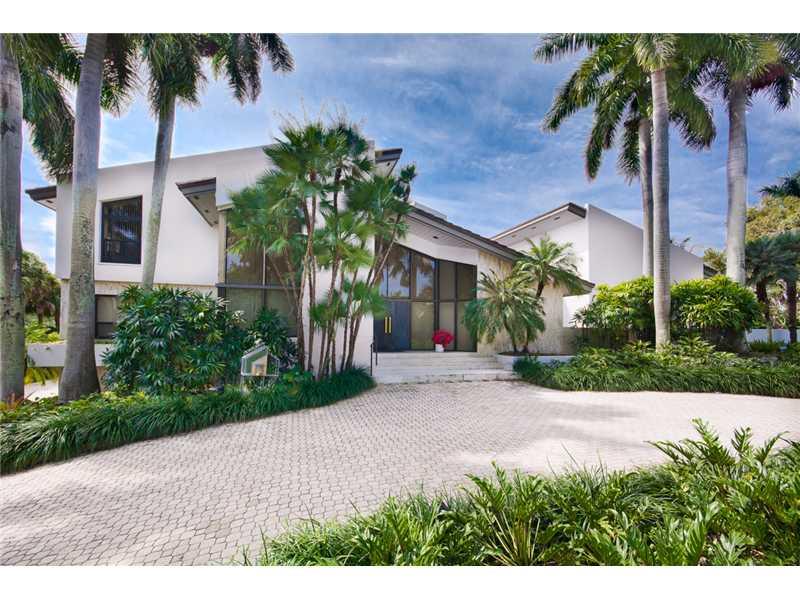 This beautiful contemporary-inspired home commands two water views.  Centered on a lushly landscaped atrium this home is filled with natural light and boasts over 10,100 adj. sq. ft. Highlights include foyer entrance, formal living room w/ wood-burning fi replace and a magnificent library lined w/ floor-to-ceiling bookcases, stained glass ceiling and herringbone wood floors, gourmet kitchen, butler's pantry, spacious family room, elevator, impact windows & doors, 125KW generator, 3-car garage & heated pool