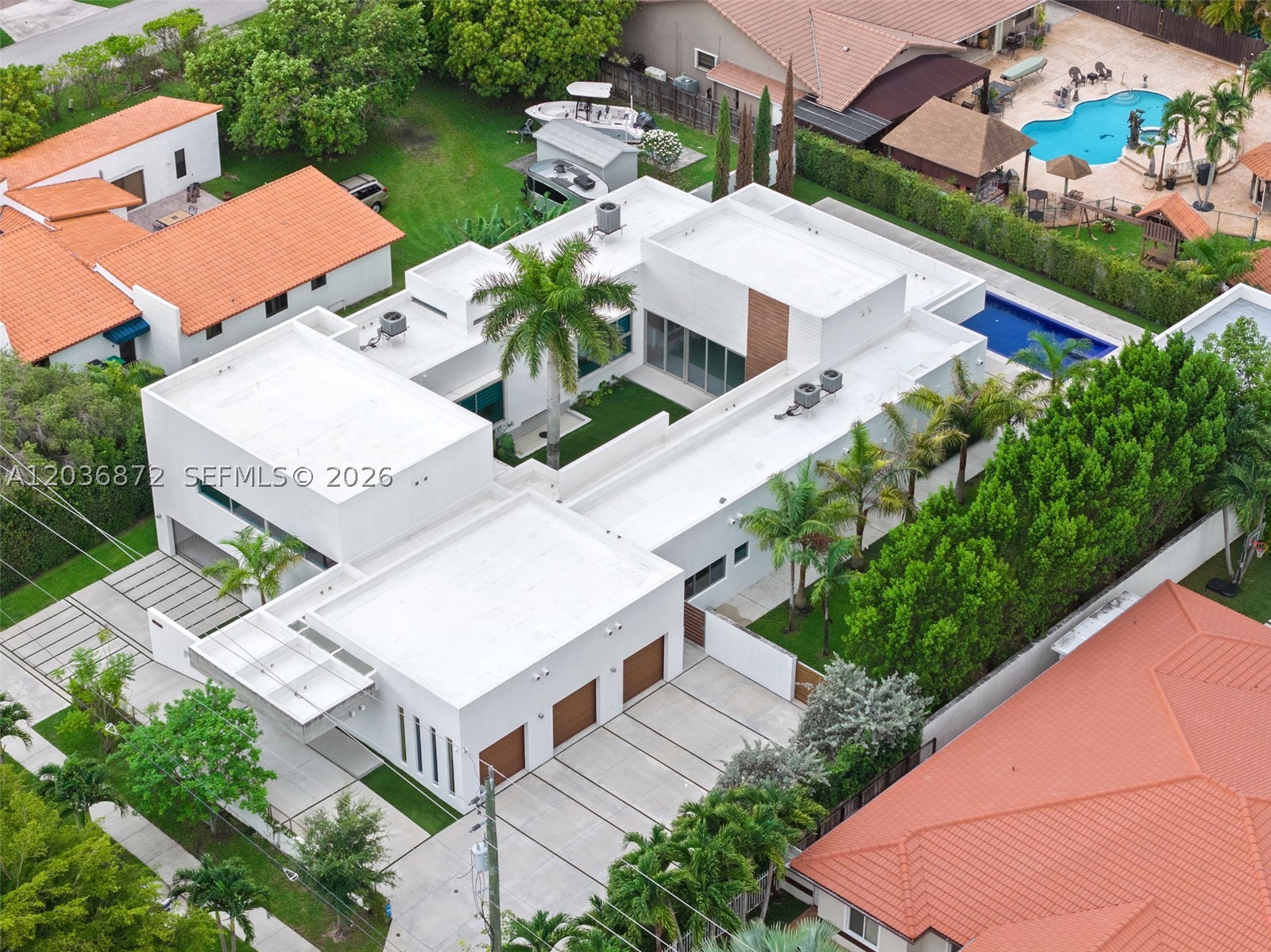 Privately commissioned and custom-built in 2018, this steel-and-concrete Architectural Estate is a rare expression of modern design, privacy, and purposeful living. Encompassing 4,146 SF of living space and 8,253 total SF on an expansive, nearly half-acre homesite (20,909 SF), the residence is organized around a dramatic open-air central pavilion that fills the home with natural light while seamlessly connecting its distinct living environments. Thoughtfully designed to balance connection and privacy, the floorplan features a private primary wing, separate guest and multi-generational accommodations, soaring ceilings approaching 20 feet, exposed architectural concrete, walls of impact glass, and refined contemporary finishes throughout. Expansive retractable glass walls dissolve the boundary between indoors and out, opening to a heated 60-foot swimming pool, covered terraces, a detached culinary pavilion with summer kitchen and event storage, and western exposures capturing beautiful South Florida sunsets. Equipped with Control4 whole-home automation, a secured two-level six-car garage including a lower-level vehicle gallery and storage space, circular motor court, covered carport, and parking accommodations for approximately 15 vehicles. A truly one-of-a-kind contemporary estate designed with purpose, built without compromise, and created to be experienced. Exceptional location in Miami's Western Coral Way corridor. There is no other in comparison.