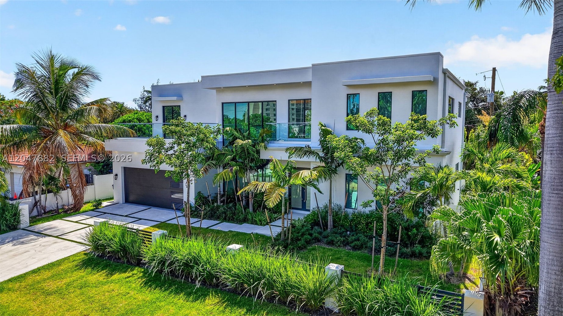 This new-construction 4BD/4.5BA residence offers dramatic architecture, rare scale, and a low-maintenance lifestyle just steps from Wilton Drive’s restaurants, cafés, nightlife, and local energy. A home made for hosting, features include soaring 24’ ceilings, a floating glass staircase, private elevator, enclosed glass catwalk, and abundant natural light. The open main level is built around gathering, with generous living and dining areas, a sleek kitchen with Italkraft cabinetry, quartz countertops, Miele appliances, and a wine cooler. The flexible layout includes two primary suites, one on the main level and one upstairs, plus two guest bedrooms, a 2-car garage, and laundry on both levels. Two upper-level terraces offer views over the neighborhood and surrounding greenery, creating a quiet setting for morning coffee, evening cocktails, or a peaceful outdoor escape. The intimate yard is relaxed and easy to maintain, with an outdoor kitchen, oversized saltwater spa, and plunge pool. Never lived in and priced at a compelling value, this nearly 3,800 sq ft residence stands out in Wilton Manors with a striking design and meaningful long-term potential.
