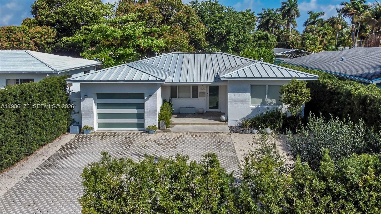 Adorable and beautifully updated, this 2-bedroom, 2-bath home with a 1-car garage offers the perfect blend of comfort, style, and functionality—overlooking a beautiful multimillion dollar newly renovated golf course. From the moment you arrive, you’ll appreciate the inviting covered front porch, lush privacy hedge, and ample parking for at least three cars.

Step inside to a spacious, light-filled layout featuring wood flooring throughout, a generous living room, formal dining area, and a charming Florida room—ideal for relaxing or entertaining. The open, updated kitchen is designed to impress with shaker-style cabinetry, quartz backsplash, and stainless steel appliances, creating a warm and modern centerpiece of the home.

Both bathrooms have been tastefully renovated with high-end finishes, including marble flooring, glass-enclosed showers, and stylish vanities, with the second bathroom showcasing a sleek floating sink.

The garage has been thoughtfully finished with a concrete floor and is currently used as a TV/family room, offering flexible living space to suit your needs. Step outside to a private backyard with room for a pool, complete with a mango tree and olive trees—your own tropical retreat.

Additional highlights include impact doors and some impact windows, a newer PVC fence, a metal roof (approx. 2020), and a water heater just 3 years old, providing peace of mind for years to come.