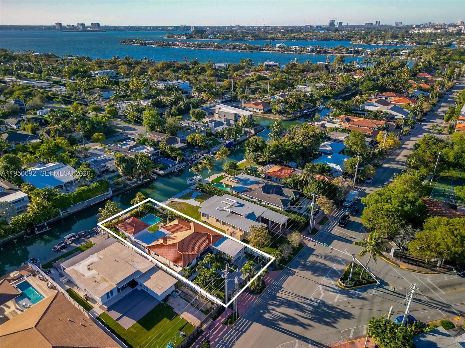 Experience the best of Miami Beach waterfront living in this beautifully modernized 4BD/3BA gated residence set on a 9,000 SF lot with 60 FT of water frontage, a private dock, a brand-new seawall, and no fixed bridges—ideal for boating enthusiasts. The home features light-filled interiors, impact glass throughout, and a thoughtfully designed open floor plan, while the gourmet gas kitchen with stainless steel appliances flows seamlessly into the main living areas. The primary suite offers a walk-in closet, a spa-like bathroom with a separate soaking tub, glass-enclosed shower, dual vanities, and direct access to the backyard. The main residence is complemented by a newly built detached guest house with an additional bedroom and bathroom (2,311 sq ft combined)—perfect for extended family, or home office. The outdoor space also includes a heated saltwater pool, hot-water shower, and a spacious covered patio with outdoor kitchen for effortless entertaining.