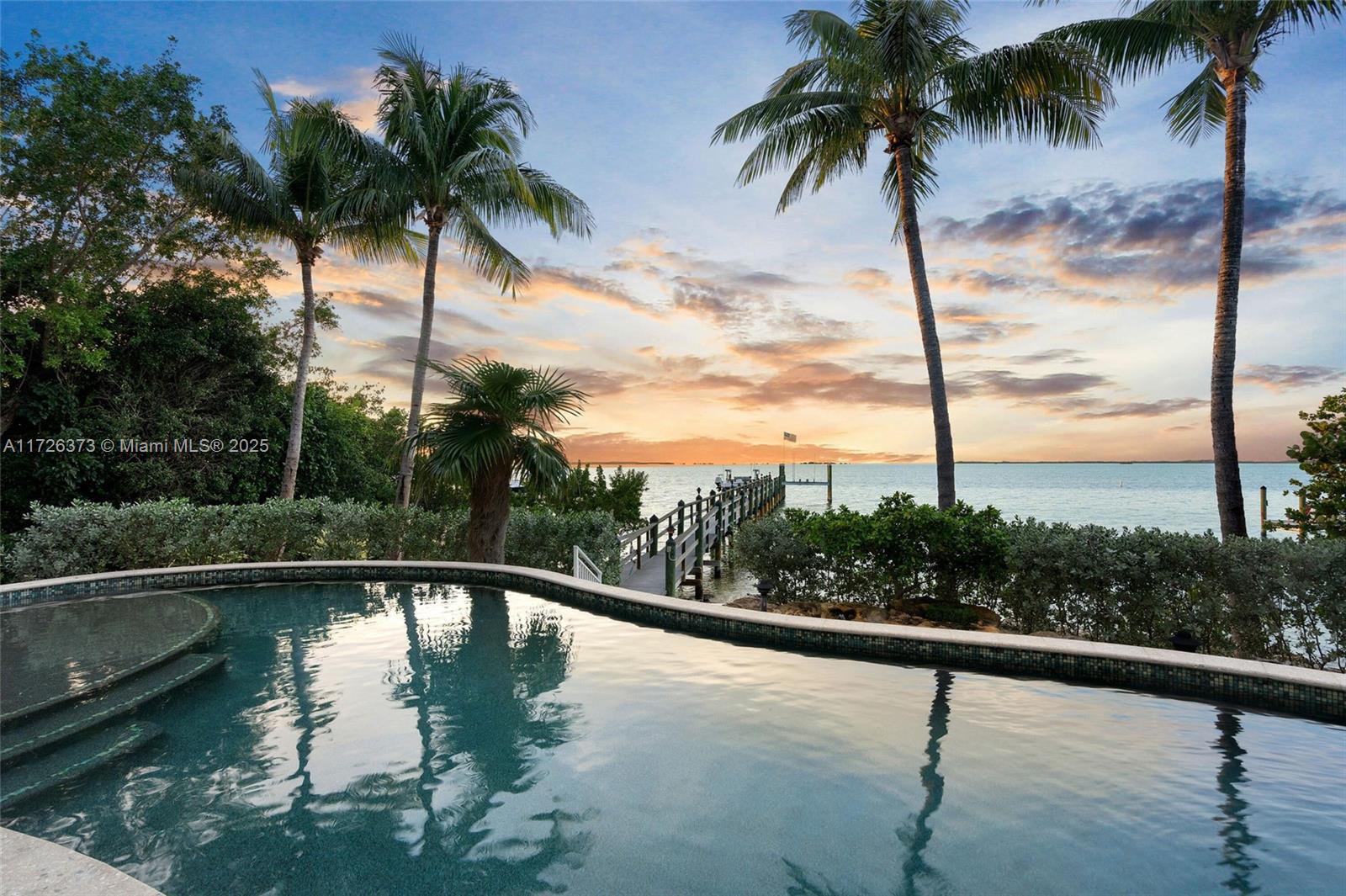 Nestled within the exclusive gated enclave of Coral Coast, comprised of only 15 private waterfront estates, this exceptional Bayfront residence offers a rare combination of privacy, security, breathtaking open-water views, and a coveted sandy-bottom beach shoreline ideal for the relaxed coastal lifestyle buyers seek in the Upper Keys. This custom-built estate captures sweeping views of Florida Bay and Everglades National Park from nearly every room. Spanning over 6,000 square feet across three levels with elevator access to all floors, the home features 5 bedrooms, 6 full baths, and 2 half baths. Warm Brazilian walnut hardwood floors, soaring ceilings, and expansive living spaces create an inviting yet sophisticated atmosphere. The gourmet kitchen is designed for entertaining with Monogram appliances, gas range, oversized island, breakfast bar, custom cabinetry, and a breakfast nook overlooking the Bay. The thoughtful floor plan includes two guest suites on the main level, a Bayfront office/study with private bath, and expansive living and dining areas designed to maximize the stunning waterfront setting.
Occupying its own private wing on the upper level, the Owner’s Suite offers panoramic Bay views, a spa-inspired bath with jet tub overlooking the water, double vanities, walk-in shower, private balcony, and spacious walk-in closet. An additional guest suite completes the third floor.