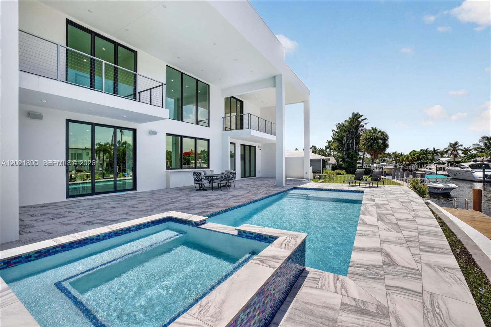 Experience upscale coastal living in this newly completed 2025 contemporary waterfront residence featuring an elevated 80-foot deepwater dock with full electric service, no fixed bridges, and direct Intracoastal and ocean access. Over 4,000 SF of refined luxury in the heart of South Florida, this exceptional 4BR/4BA/1HB home seamlessly blends elegant indoor and outdoor living. Soaring ceilings, expansive floor-to-ceiling impact-resistant glass, motorized shades, sun-filled interiors frame breathtaking ocean-access water views. The designer chef’s kitchen showcases an oversized double-slab black island, premium appliances, gas cooktop, and sophisticated finishes ideal for intimate dining or large-scale entertaining. Upstairs, rich hardwood flooring leads to the luxurious primary suite with private sitting area/office, spa-inspired bath with dual sinks and showers, freestanding soaking tub, bidet, oversized walk-in closet, and covered balcony overlooking the canal. All bedrooms feature en-suite baths and walk-in closets, while two upstairs balconies capture wide-water views. Resort-style outdoor spaces include an expansive entertaining area, plumbing ready for a future summer kitchen, and a spectacular waterfront pool & spa designed for elegant outdoor living. Additional highlights include solar panels, gas generator, smart home integration, indoor/outdoor audio security cameras, 10 ft high garage doors and future rooftop entertainment possibilities with panoramic water views.