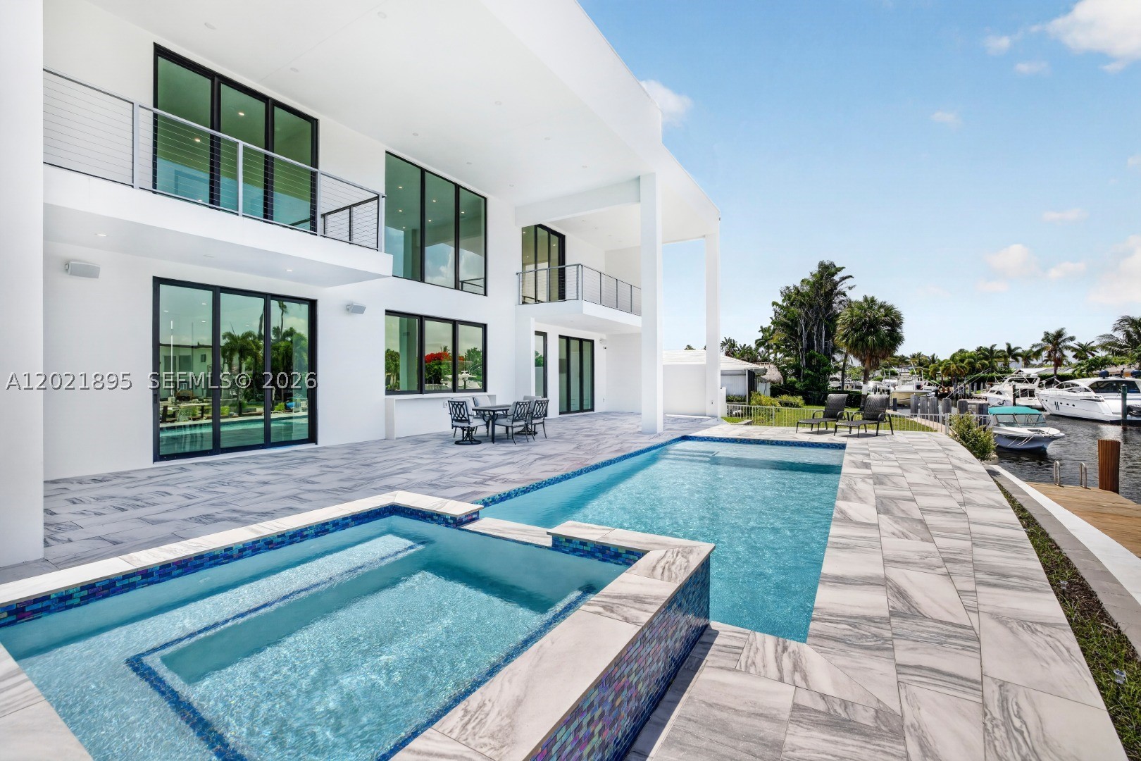 Experience upscale coastal living in this newly completed 2025 contemporary waterfront residence featuring an elevated 80-foot deepwater dock with full electric service, no fixed bridges, and direct Intracoastal and ocean access. Over 4,000 SF of refined luxury in the heart of South Florida, this exceptional 4BR/4BA/1HB home seamlessly blends elegant indoor and outdoor living. Soaring ceilings, expansive floor-to-ceiling impact-resistant glass, motorized shades, sun-filled interiors frame breathtaking ocean-access water views. The designer chef’s kitchen showcases an oversized double-slab black island, premium appliances, gas cooktop, and sophisticated finishes ideal for intimate dining or large-scale entertaining. Upstairs, rich hardwood flooring leads to the luxurious primary suite with private sitting area/office, spa-inspired bath with dual sinks and showers, freestanding soaking tub, bidet, oversized walk-in closet, and covered balcony overlooking the canal. All bedrooms feature en-suite baths and walk-in closets, while two upstairs balconies capture wide-water views. Resort-style outdoor spaces include an expansive entertaining area, plumbing ready for a future summer kitchen, and a spectacular waterfront pool & spa designed for elegant outdoor living. Additional highlights include solar panels, gas generator, smart home integration, indoor/outdoor audio security cameras, 10 ft high garage doors and future rooftop entertainment possibilities with panoramic water views.