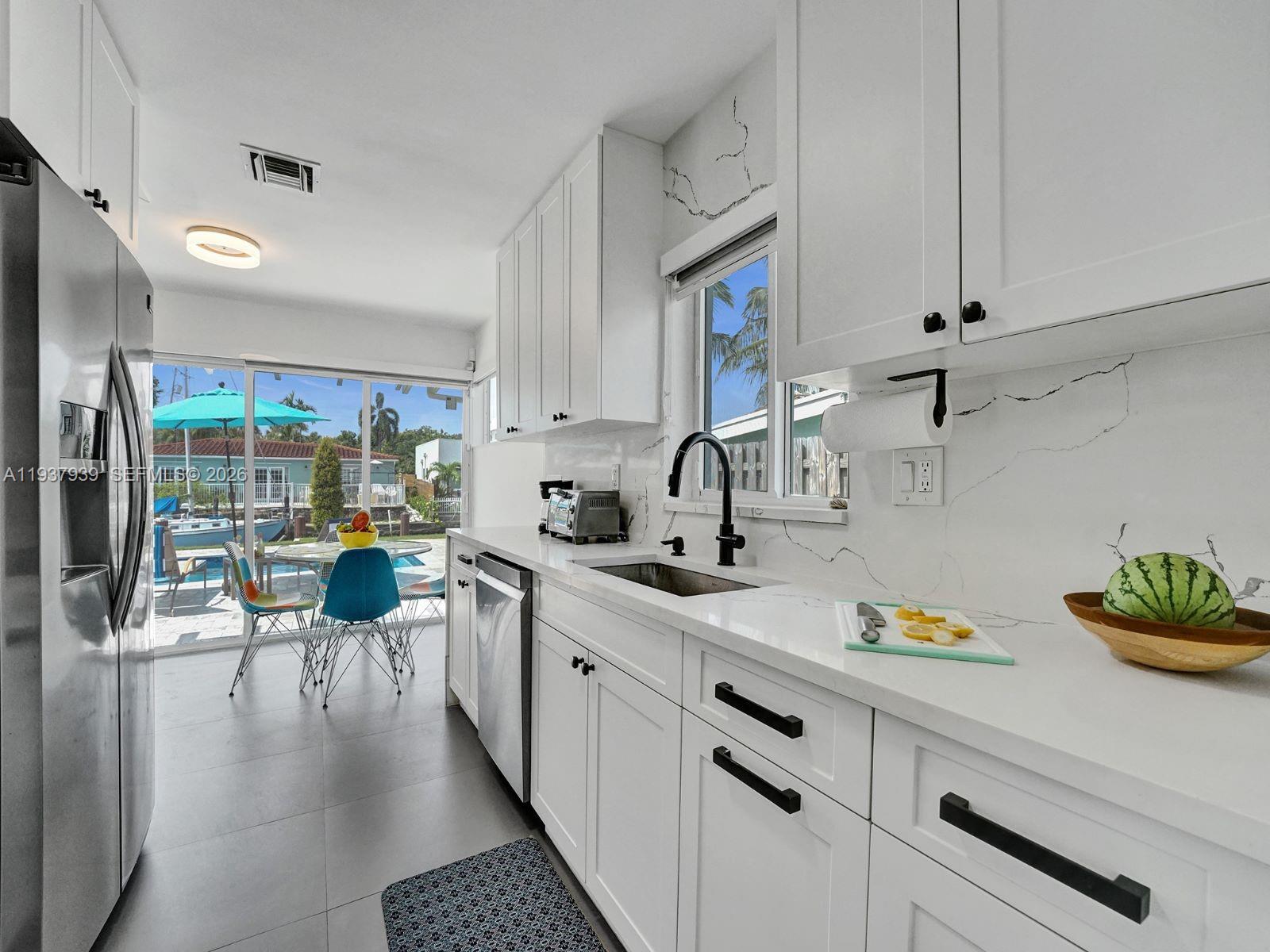 Experience waterfront living at 1108 Tangelo Isle, a beautifully renovated 3-bedroom, 2-bathroom single-family smart home in the heart of Fort Lauderdale. This turn-key residence features 65 feet of private waterfrontage on a deep-water canal with ocean access and no fixed bridges, making it an ideal choice for boating enthusiasts. The interior has been fully updated with a fresh, modern aesthetic, featuring a windowed galley kitchen with stainless steel appliances and tile flooring throughout. Both bathrooms have been completely renovated to offer contemporary finishes. The home’s layout emphasizes a connection to the private outdoor oasis, where a below-ground pool and an expansive patio provide ample space for relaxation or entertaining. Equipped with full impact-rated glass doors and windows and featuring desirable southern exposure, this move-in-ready home offers the perfect blend of modern security and classic Isles charm.