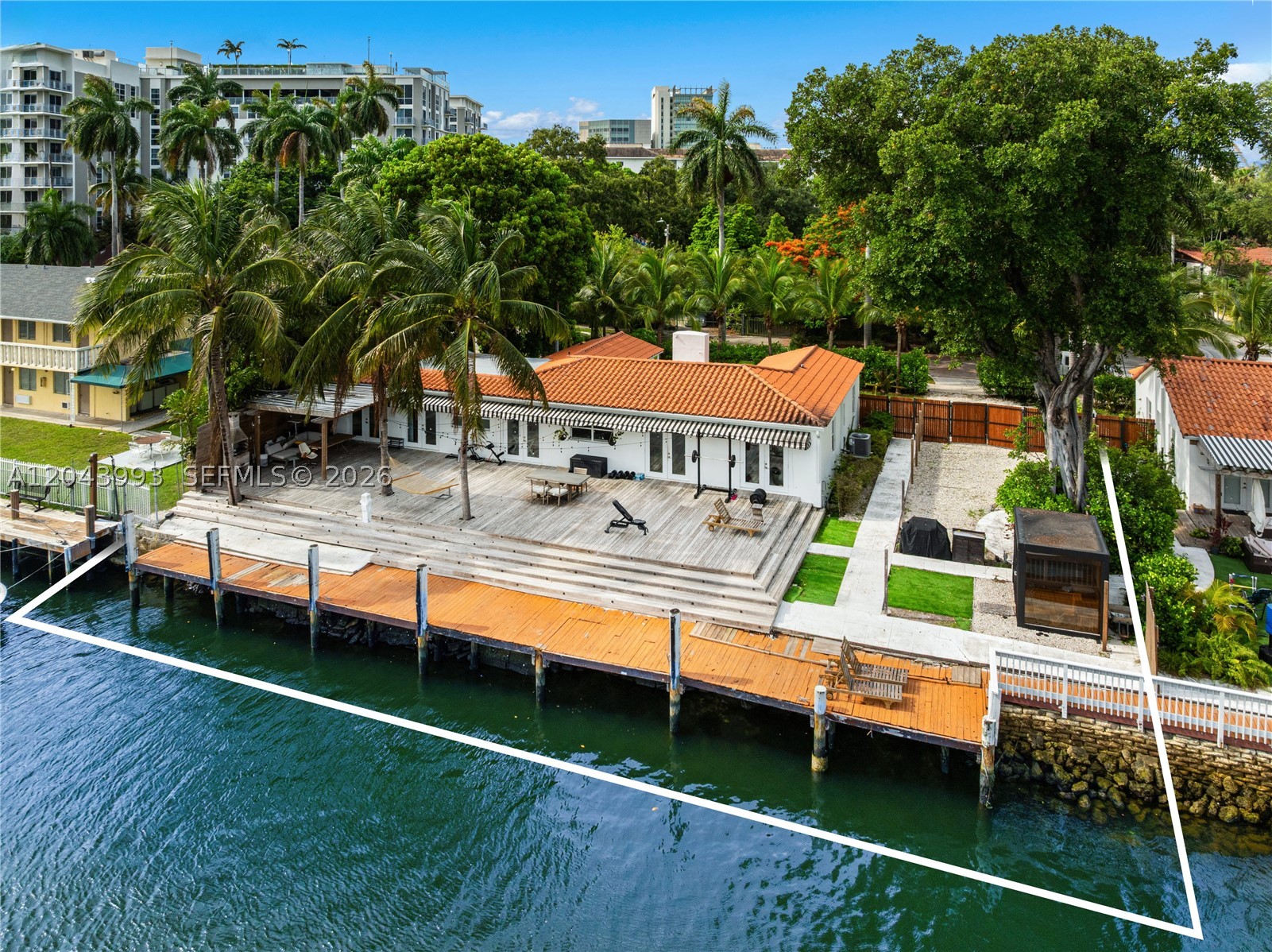 A rare riverfront offering in historic Spring Garden, one of Miami’s most charming and centrally located neighborhoods. Set on a deep 13,915 SF lot with 98 feet of Miami River frontage, this renovated 4BD/3BA residence pairs warm architectural character with a true boater’s lifestyle. Interiors span 2,195 SF and feature soaring wood-beam ceilings, stone flooring, generous living and dining areas, and a center-island kitchen opening through French doors to an expansive waterfront deck. Outside, a large private dock creates an exceptional setting for boating, entertaining, and enjoying the energy and movement of the Miami River. Sited in a tranquil, canopied neighborhood known for its broad streets, large lots, mature shade trees, and two parks, the home offers a rare blend of historic character, waterfront living, and immediate proximity to Downtown, Brickell, Wynwood, Miami Beach, the Health District, and Miami International Airport.
