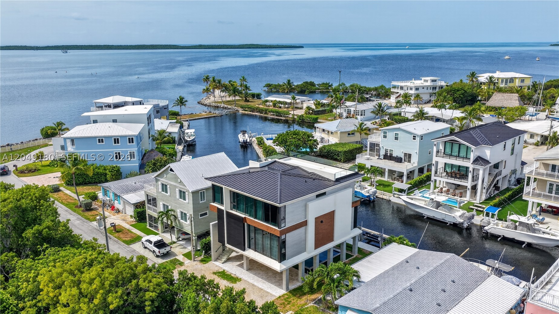 Experience the ultimate in modern waterfront luxury with this brand-new concrete masterpiece, thoughtfully designed for both elegance and durability. Boasting 4 bedrooms and 4 bathrooms, this stunning residence offers breathtaking ocean views, a protected canal location, 55 feet of dockage, and 15,000 lb boat lift for effortless boating access. Built to the highest standards with a concrete roof, impact-resistant windows and doors, and an elevator servicing all levels, this exceptional home blends sophisticated design with everyday convenience. The show- topping custom Italian kitchen is beautifully appointed with premium Miele appliances, sleek cabinetry, and designer finishes, creating the perfect space for entertaining. Step outside to your private backyard oasis featuring a sparkling saltwater pool with premium equipment, ideal for relaxing after a day on the water. Additional luxury features include whole-home surround sound, a security camera system, and high-end finishes throughout. Located in an exclusive private community with a clubhouse for special events, this property combines luxury, security, and the Florida Keys waterfront style.