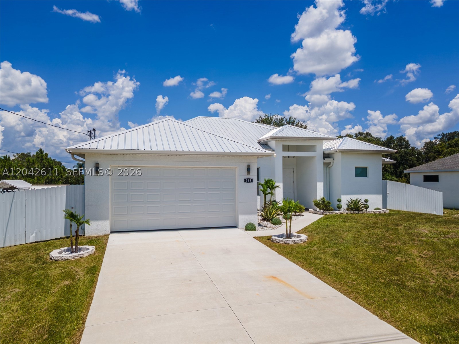 Enjoy tranquil golf course views from this newly constructed Lehigh Acres residence, thoughtfully designed with a blend of modern style and everyday functionality. Soaring ceilings create a bright, open feel throughout the home, enhanced by designer ceiling fans and an elegant chandelier that anchors the dining area. The thoughtfully designed kitchen features sleek quartz countertops, stainless steel appliances, ample cabinetry, and a pantry, seamlessly connecting to the main living spaces for effortless entertaining. Tile flooring flows throughout the interior, while French doors add architectural charm and natural light. The spacious primary suite offers a spa-inspired bath with dual sinks, a separate tub, and shower. A versatile den or office provides flexibility for work, hobbies, or additional living space. Built with durability and peace of mind in mind, the home includes hurricane-impact windows and sliding glass doors along with a metal roof. Outdoors, the private fenced backyard offers plenty of room to relax, entertain, or add a future pool, all while enjoying picturesque golf course views. A rare opportunity to own a stylish, move-in-ready new construction home in a growing Lehigh Acres location.
