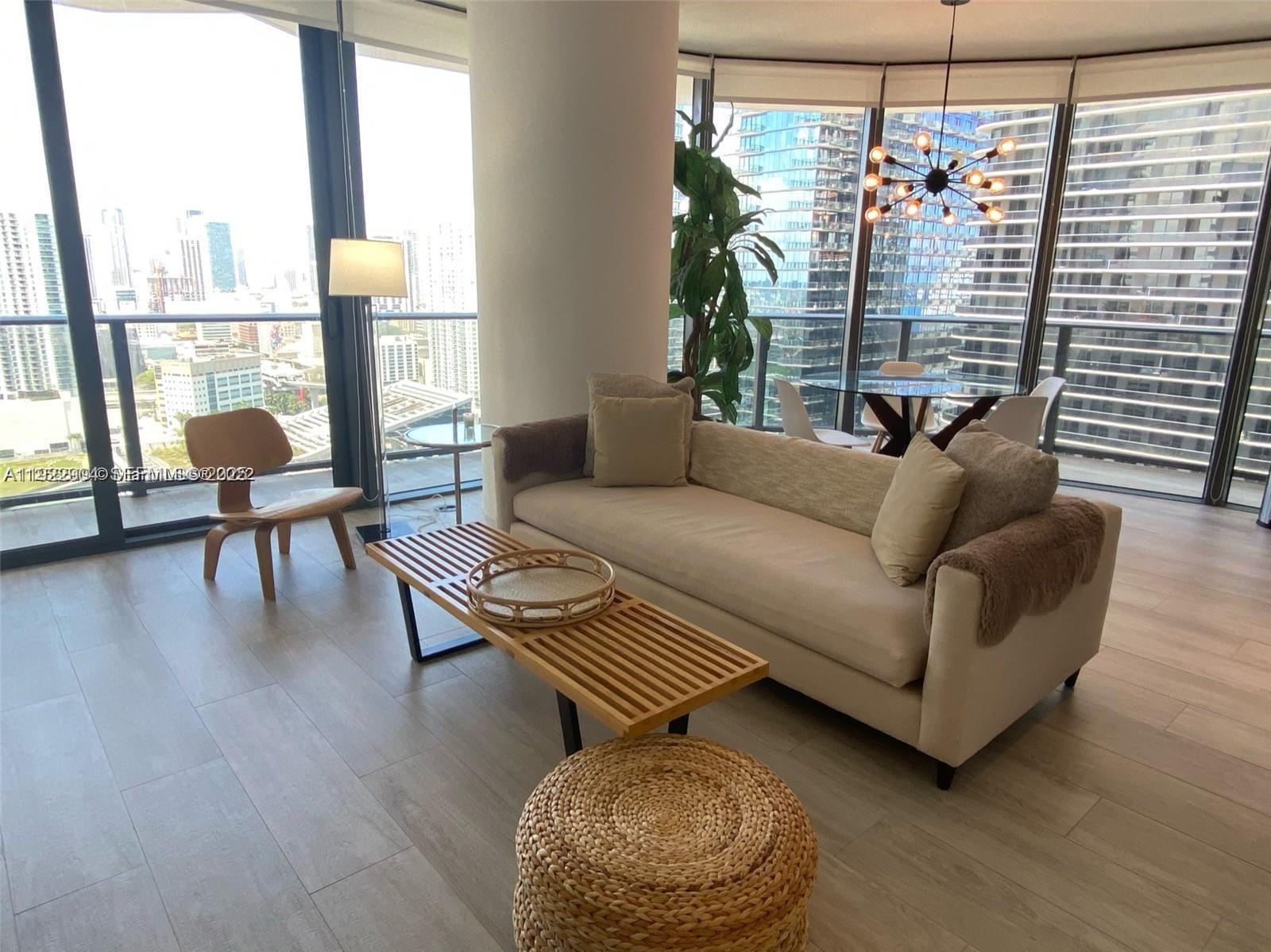 With a huge wrap-around balcony offering panoramic views of the Miami River and skyline, this luxury condo is located in the heart of Brickell. Thanks to floor-to-ceiling impact glass doors and windows, the unit enjoys natural sunlight from sunrise to sunset. This corner property features a split floor plan with two bedrooms, two bathrooms, plus a den for added comfort. Delivered turnkey, it comes fully furnished and completely outfitted. Building amenities include full-service concierge, gym, spa, two rooftop pools, and much more. The unit also comes with the best parking space in the entire complex. Cable and internet are included. Currently rented until 07/01/2026, this unit is ideal for investors as the building allows short-term rentals.