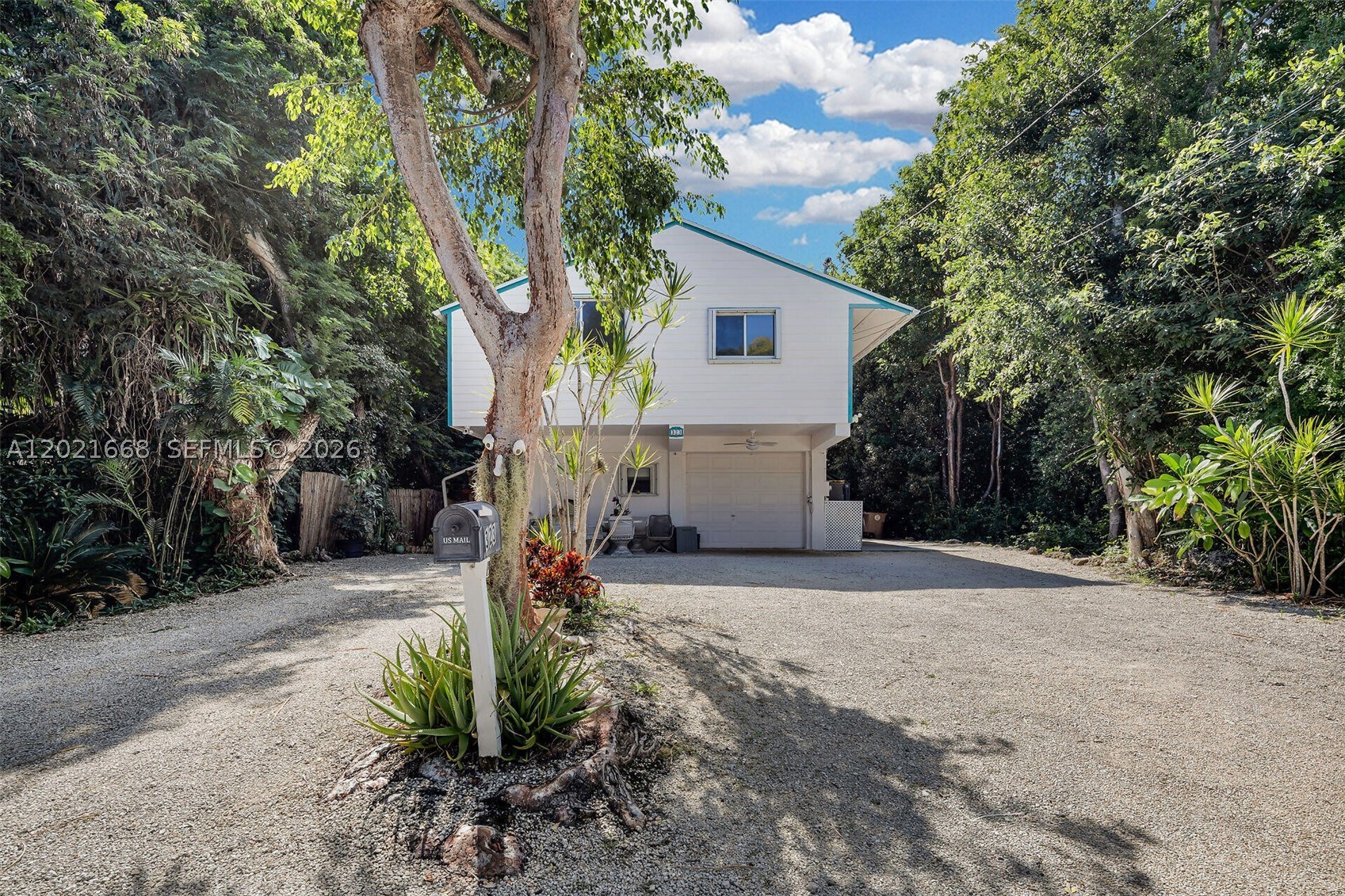 Nestled among mature tropical trees with only one neighboring property, this 3BR/2BA two-story home presents a peaceful, low-density setting just approx. 800 ft from a private homeowners’ park with beach, dock, and boat ramp for convenient access to Florida Bay. The home features an enclosed interior staircase connecting both levels, supporting its legal 3-bedroom configuration and providing a cohesive single-family layout.

The lower level is dedicated to the primary suite with ensuite bath and access to an enclosed, air-conditioned patio with large windows and a separate exterior entry—that can be used for a home office, studio, or flex space (non-bedroom). Upstairs, the open-concept living area is bright and functional, with terracotta tile throughout the main living spaces and a natural flow between living, dining, and kitchen areas. Two additional bedrooms with wood laminate flooring and a full bath complete the upper level.

Additional features include accordion hurricane shutters, ceiling fans, recessed lighting, two separate A/C systems, and two water heaters (2022 A/C and 2023 water heater upstairs). The property also has a one-car garage/workshop, exterior-access storage, and ample parking for multiple vehicles, a boat, or RV. Surrounded by established tropical landscaping, this property presents a unique combination of setting, layout, and proximity to water access.