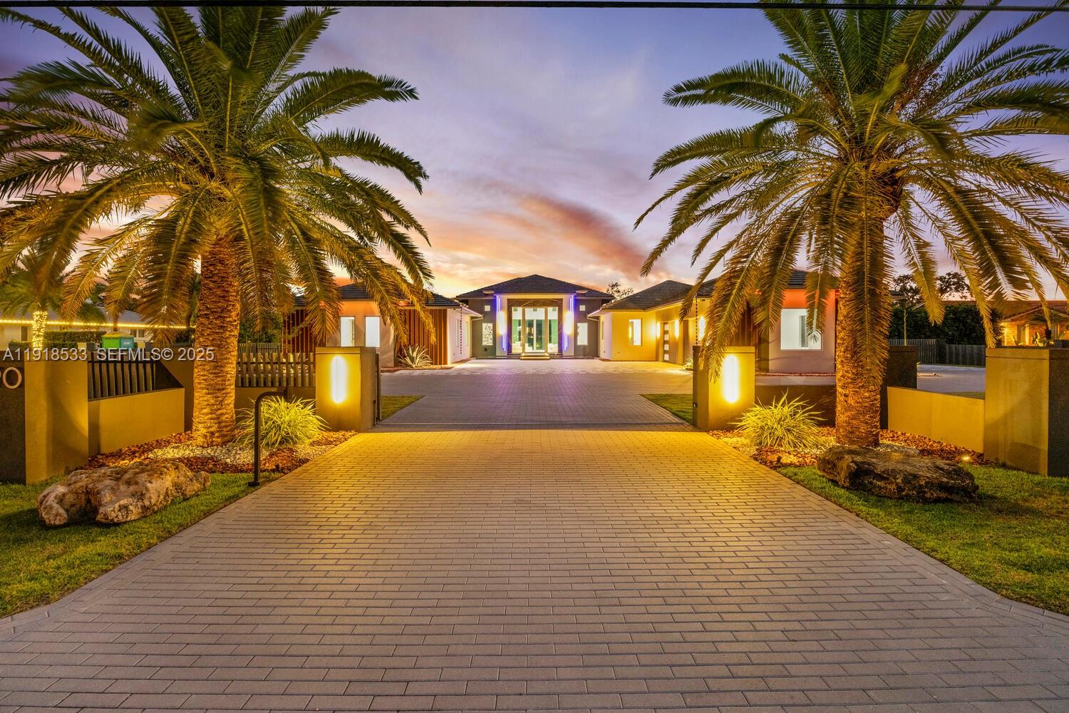 Experience modern luxury in this exceptional 1-story estate offering 6 bedrooms, 6.5 baths, and 8,067 sq ft of living space on 1.25 lush acres. A 12-ft pivot glass door and soaring 15 ft ceilings set a grand tone for refined interiors with Italian porcelain floors. The chef’s kitchen includes Wolf and Sub-Zero appliances, custom cabinets, quartzite counters, a large island, and a cable wine display. A glass-wrapped sunroom opens to the summer kitchen and patio. Enjoy a 70-ft knife-edge pool, 10×14 overflow spa, fire-pit lounge, half basketball court, and 3-car garage.