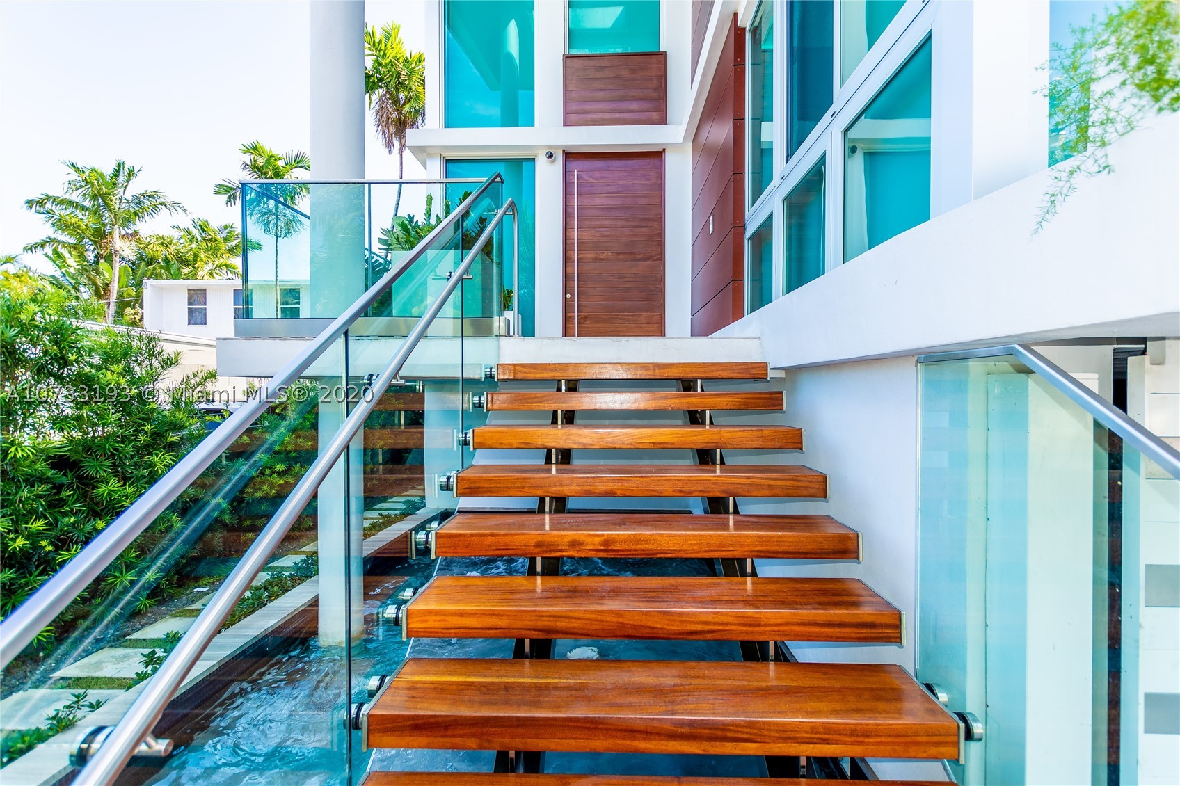 Bayfront. Spectacular. Exclusive. This Reinaldo Borges-designed trophy home on Miami Beach's exclusive Palm Island is a model of South Florida's world-famous tropical luxury lifestyle. Sunshine pours in everywhere through wrap-around glass walls & floor-to-ceiling windows. The infinity pool and 1,600 SF rooftop terrace overlook the water and cruise harbor, broadening the residence's exotic resort ambiance. The fabulous custom floating wood staircase, 20-ft ceilings, enormous dual-island La Strada kitchen, 90-bottle wine cooler, and spa-like atriums number a few more highlights of the home's magazine-worthy design. The property is boat-ready, with a private dock & lift. Bonus features incl. a Florida room, staff or guest rooms, an elevator, and a 2-car garage. 6BD / 7.5BA / 6,139 SF