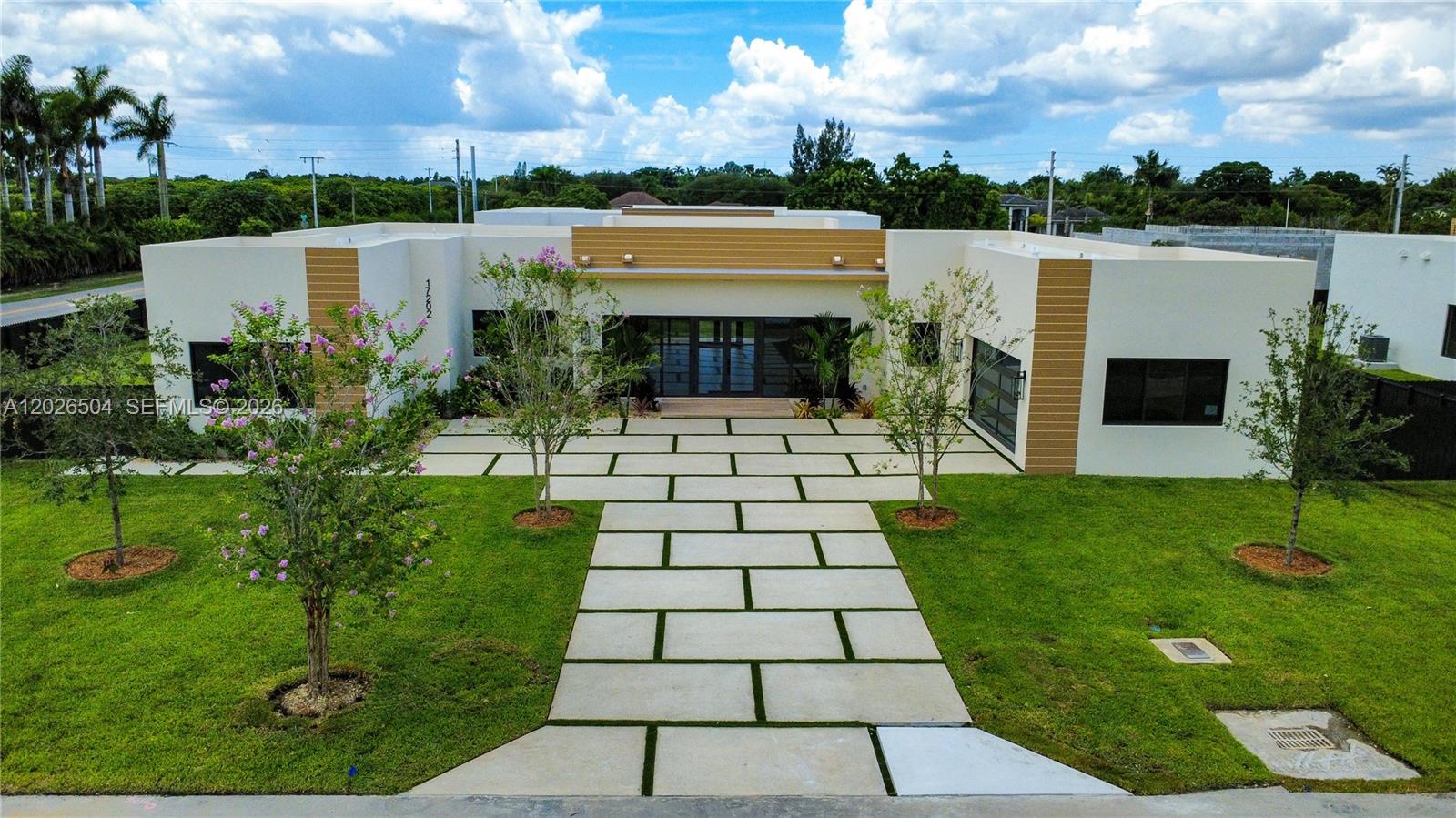 Stunning modern CBS luxury new construction featuring a sleek flat TPO roof, hurricane-impact windows and doors, and a concrete-built, storm-hardened/bunker-style structure for maximum durability and protection. Situated on a spacious 17,025 sq ft lot, this property showcases a sealed and polished driveway with turf accents, a double car garage, and professionally landscaped grounds with sprinkler system. Enjoy front and rear terraces for seamless indoor-outdoor living.

Inside, the home offers soaring 110ft ceilings and porcelain flooring throughout, complemented by panel wood interior doors, recessed lighting, and designer fixtures. Equipped with two tankless water heaters and dual A/C systems for efficiency and comfort.

The chef's kitchen features modern wood cabinetry to the ceiling, quartz countertops, waterfall island, and stainless steel appliances including ceramic cooktop, slide-in range, drawer microwave, hood, dishwasher, and smart refrigerator.

Bathrooms include wood cabinetry and quartz finishes. The primary suite offers a spacious walk-in closet. A/C laundry room with washer/dryer included.

Separate in-law quarters include a private bedroom, full bathroom, living area, and its own laundry ideal for extended family or guests.
