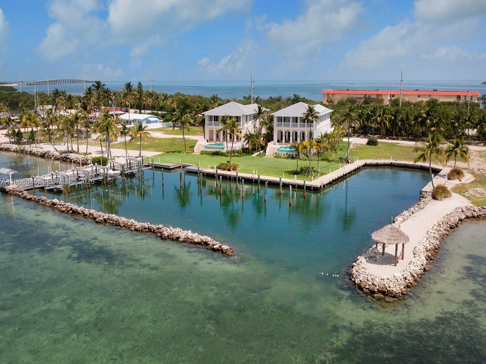 An unparalleled development opportunity in the heart of the Florida Keys. Spanning approximately 10 acres, this expansive bayfront property represents one of the largest and most versatile land offerings currently available in the Middle Keys. There are two newer construction homes (4 bedrooms/4.5 bathrooms each), 8 additional building rights (7 waterfront lots, 1 dry lot), 16 deep water boat slips in a protected basin (6 with boat lifts) and a total of 10 acres of land conveyed with the sale. The property offers exceptional flexibility for a luxury compound, secluded waterfront community or private family retreat. 

The 2 current homes sit on 5,200 SF lot each featuring 4 bedrooms/4.5 bathrooms with a total interior square footage of 3,300. Each has their own private pool & spa, unobstructed bay views, garage, Thermador appliances & marble kitchen countertops, impact doors & windows & designed to embrace the island lifestyle. The estate balances seclusion with convenience just minutes from Marathon Executive Airport for effortless fly-in, fly-out access. As well as seamless access to both the bay & ocean side waters via Long Key Bridge or Channel 5. The setting is defined by endless sunsets, abundant wildlife, and world-class boating & fishing just steps from your door. Whether envisioned as a multigenerational retreat, a private waterfront sanctuary or a visionary redevelopment, this legacy property offers the space, flexibility & natural beauty to bring a dream to life.
