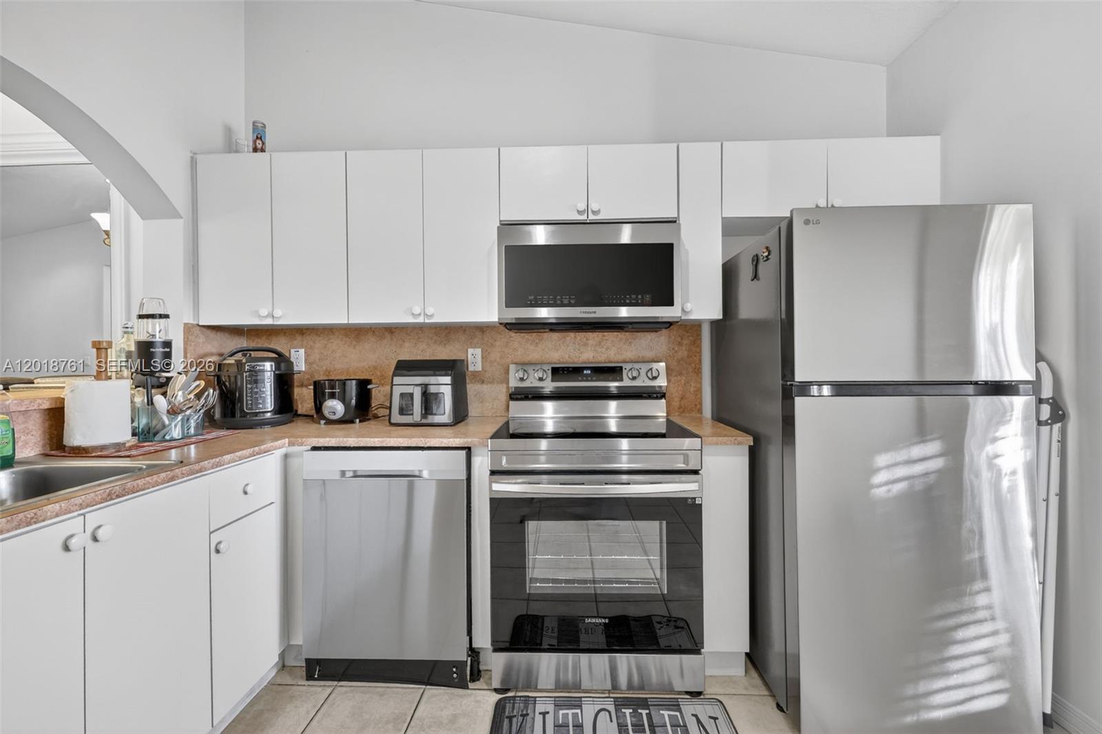 Charming 2BD/2BA second-floor condo in a well-maintained lakeside community in Homestead. Featuring soaring vaulted ceilings, elegant arched doorways, and an open-concept living and dining area with chandelier lighting and tile flooring throughout. The kitchen boasts white cabinetry, stainless steel appliances, a tile backsplash, and a convenient pass-through to the dining area. Both bedrooms feature laminated flooring and ceiling fans. In-unit stacked washer/dryer included. Enjoy serene lake views from the kitchen and master bedroom. Community amenities include a resort-style pool surrounded by lush tropical landscaping, all set on a beautiful lakefront property. Publix supermarket conveniently located right across the street. Low HOA of only $345/month. Currently tenant-occupied at $1,800/month through June 30th — a great opportunity to start collecting rent from day one! Association allows immediate rental, making this an ideal turnkey investment. Easy access to major highways, shopping, and dining. Don't miss this one!