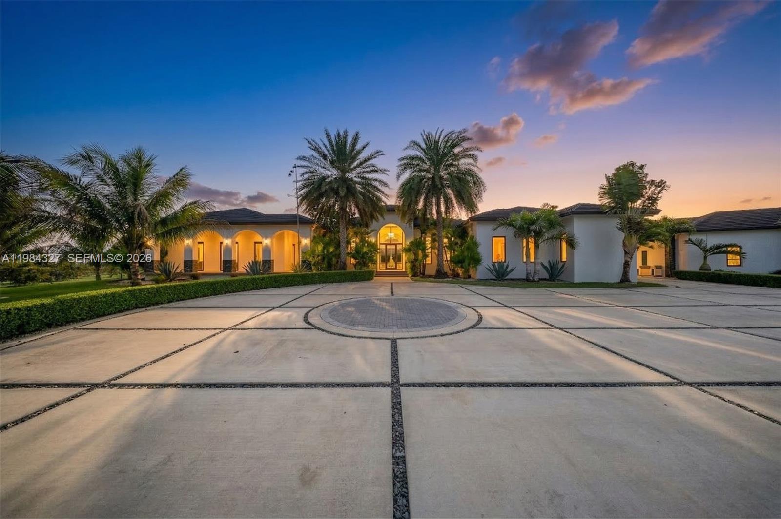 Welcome to Arrow Estate — a modern contemporary masterpiece on over 5 acres in Miami Dade County, near West Kendall and the Redlands. Built in 2023, this architectural gem offers 7 bedrooms, 6 bathrooms, and over 8626 sq ft, 11,835 adjusted sq ft, within 15,391 total sq ft under roof. A grand double-height foyer with 17-ft ceilings, floor-to-ceiling impact glass, and crystal chandeliers opens to expansive living areas and a chef’s kitchen with Liebherr refrigeration, Monogram appliances, induction cooktop, wine cooler, and oversized walk-in pantry. Bathrooms feature Duravit fixtures, smart mirrors, and bidet-equipped floating toilets. Ceramic tile floors run throughout, complemented by custom German doors. Four primary suites include spa-style baths, rainfall showers, soaking tubs, and custom closets; the main suite offers a lounge and pool access. Additional spaces include an office, media room, family room, art studio, and full laundry with LG appliances. Outdoors, enjoy a 20x40 infinity pool, sunken bar, built-in BBQ, and natural stone terraces ideal for entertaining. The property also features a 6-car garage, barn with kitchen and bath, casita, and multiple structures with future guest potential, plus 355 tropical fruit trees producing with AG exemption, a gas-powered generator with a 1,200-gallon tank, and no HOA.