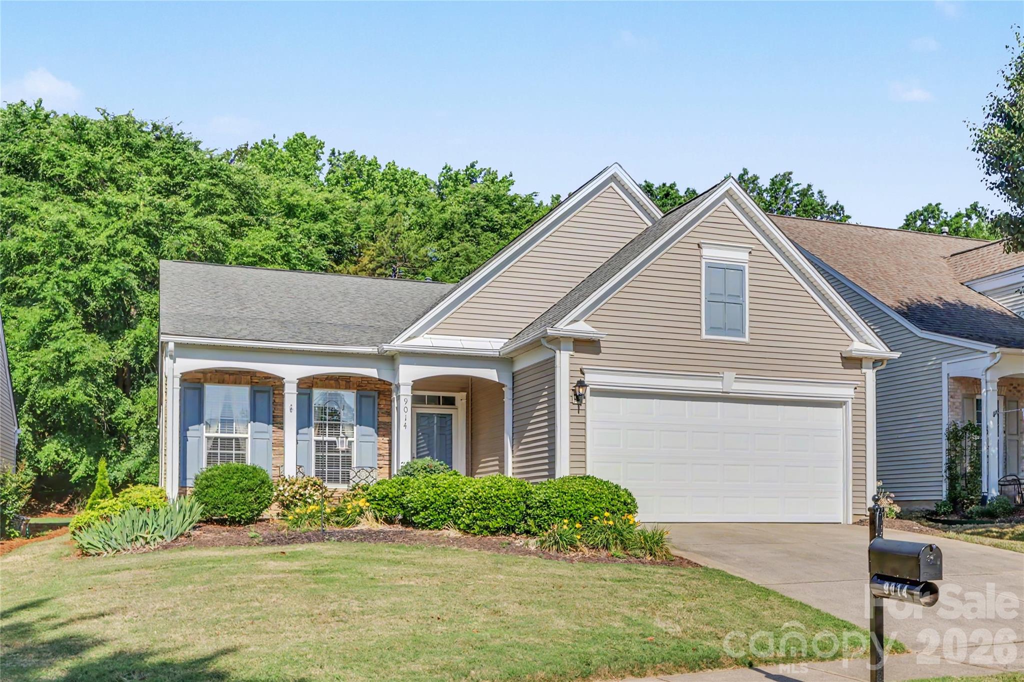 Former Pulte® model home in pristine, move-in-ready condition offering an easy, carefree lifestyle with lawn maintenance included. This beautifully maintained 2-bedroom, 2-bath ranch features a welcoming covered front porch. French doors open to a private office/flex space perfect for working from home or a quiet sitting room. The home also offers a designated dining room ideal for entertaining, along with elegant details throughout, including tray ceilings, chair rail molding, and custom window treatments. The spacious kitchen features stainless steel appliances, abundant cabinetry, and a large center island overlooking the breakfast area and great room with gas fireplace, creating an inviting open layout ideal for everyday living and entertaining. The great room and breakfast area enjoy serene wooded views, with active bird feeders creating a peaceful natural setting right outside your windows. Relax year-round on the private screened porch with added roll-down shades for privacy and sun protection while enjoying the private tree-lined backyard with an irrigation system. The primary suite offers large windows with tranquil backyard views, a spacious walk-in closet, and a beautifully appointed bath with safety grab bars and a raised toilet. Guest bedroom includes upgraded molding details and access to a full tiled bath. Laundry room offers custom cabinetry. The attached two-car garage includes a built-in workshop area. Enjoy true lock and go living with low maintenance convenience in an ideal location between Blakeney and Stonecrest, just minutes from I-485, shopping, dining, and everyday conveniences. Home includes an assumable VA loan with an attractive low interest rate for qualified buyers.