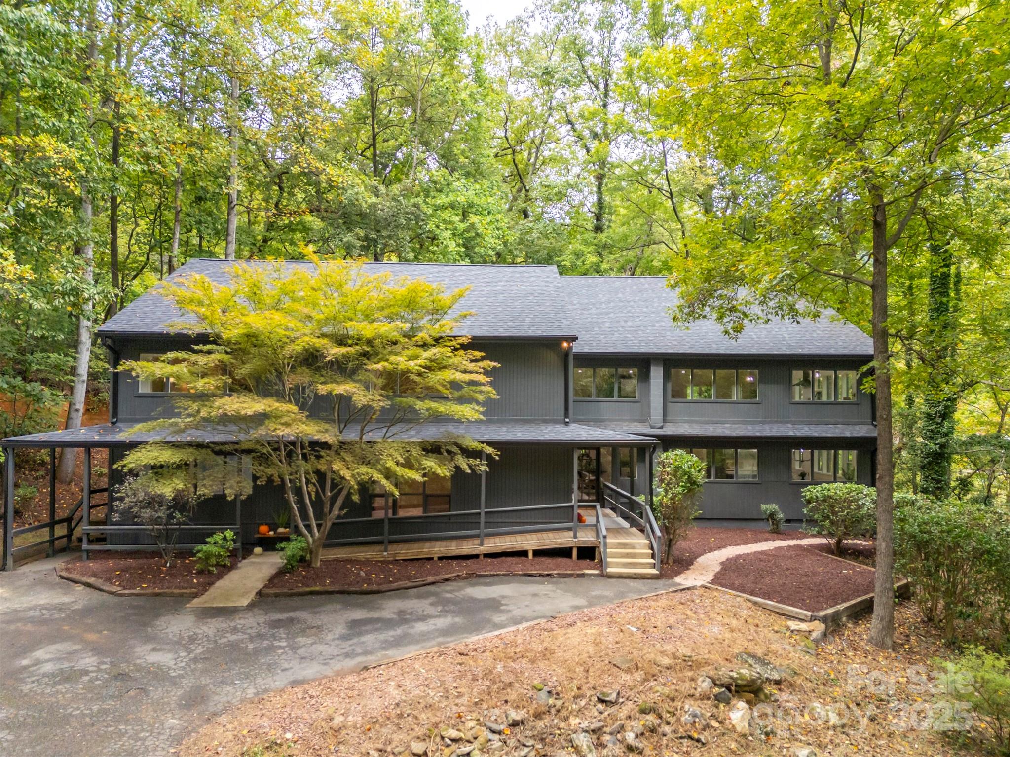 Priced $100,000 below appraised value and nestled amongst towering hardwoods on a 10acre parcel, this stunning contemporary home represents an extraordinary find.  While just minutes from downtown Tryon & I-26, the property sits at the end of a quiet cul-de-sac for optimal privacy. A gently flowing creek runs along the lower boundary line w/nature conservancy woods behind plus long range winter views.  Technically a reverse floor plan, each level boasts a full kitchen, living/great room area, primary suite and laundry - an ideal situation for multi-generational living or an investment rental property.  Impeccable finishes from the gorgeous herringbone inlay oak in the foyer to the starburst tile in the guest baths to the warm charcoal stained cabinets throughout.  Ground level features a huge mudroom/laundry w/custom drop zone cabinetry & folding island, entertainment room w/80" TV, spacious kitchen w/breakfast bar & dining area, plus a sitting/living room & convenient powder bath.  En-suite primary plus 4 additional bedrooms and 2 shared baths.  Head upstairs to a cavernous great room w/gas fireplace and rear deck.  Sleek & modern kitchen surrounded by picture windows w/ample area for dining.  Additional sitting room, bonus room & hall bath plus another laundry.  Principle primary is set apart at the end of the hall for perfect restfulness.  Lounge or reading area, spacious walk-in closet & striking walk-in tile shower with bench.  Exquisite home w/endless possibilities!  Fully inspected and ready to become the home of your dreams!