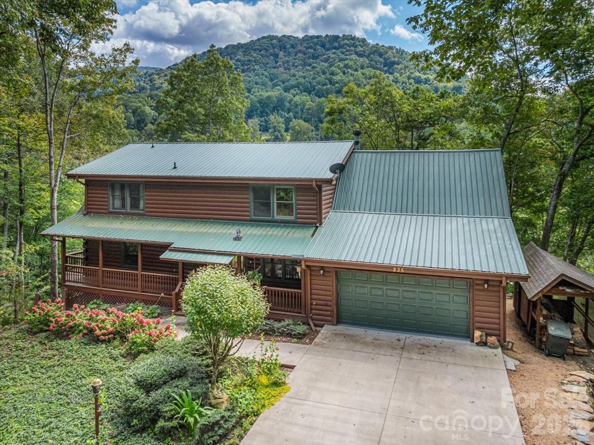 This warm and inviting, solidly built custom log home is furnished and move-in ready! Conveniently located just minutes from Historic downtown Waynesville and the Waynesville Inn and Golf Club, you will enjoy easy year-round access on wide paved city roads, city water, city sewer, plus the convenience of all city services in a peaceful setting. Enjoy year-round mountain views without the climb! The main level offers a seamless, open-concept layout highlighted by a dramatic two-story Great Room with vaulted ceilings and a stunning stone fireplace with wood stove insert. The spacious kitchen is well-appointed with solid-surface countertops, abundant cabinetry, and generous workspace, flowing effortlessly into the inviting dining area—ideal for entertaining and everyday living. The primary suite is conveniently located on the main level and includes an updated bath with a walk-in tile shower. Outdoor living is enhanced by an expansive back deck offering beautiful mountain views, perfect for entertaining, relaxing, and enjoying cool mountain evenings. The upper level includes a comfortable family room, two generously sized bedrooms, a full bath, and a flexible bonus room suitable for a home office, hobby space, or additional sleeping area. The lower level offers excellent additional living options, including a complete one-bedroom apartment with a living room, full kitchen, full bath, and a private deck—ideal for guests, live-in help, or multi-generational living. Additional features include an oversized two-car garage with workshop space and a covered shed. Whether used as a primary residence, seasonal getaway, or potential vacation rental, this well-appointed log home offers outstanding comfort, flexibility, and location. The three lots give you additional options. The community has a playground, tennis courts, and pickleball courts for residents and guests. A rare find, see it today!