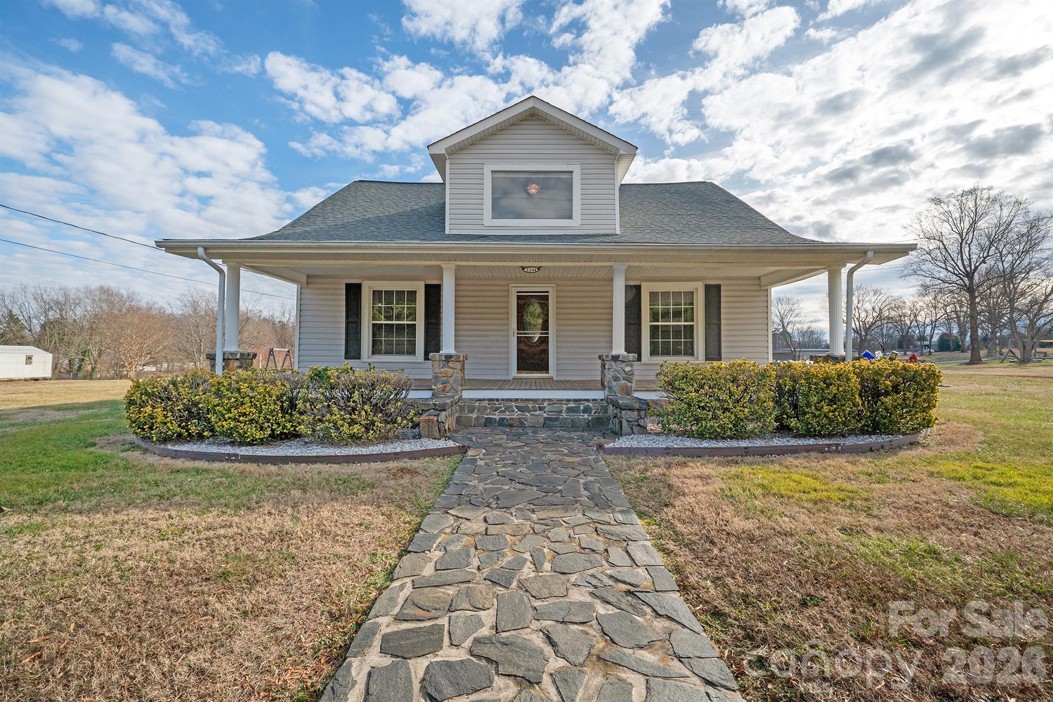 Charming 1927 Home with Modern Updates on Corner Lot . This inviting 4 bedroom, 1.5 bath home blends original 1927 character with thoughtful modern updates. A rocking-chair covered front porch welcomes you, complemented by a stone walkway and classic curb appeal. Inside, a wide, inviting foyer showcases hardwood floors and sets the tone for the home’s warmth and charm. The cozy den features a gas freestanding fireplace, perfect for relaxing evenings. A formal dining room offers laminate “tile” flooring and built-in cabinet, ideal for entertaining. The spacious kitchen provides ample room for cooking and gathering, with access to a side deck for outdoor enjoyment. The main level offers two bedrooms, both with hardwood floors, a separate laundry room, and a full bath with tub/shower, along with access to the back patio. Upstairs, you’ll find two additional bedrooms, an office, and a half bath, with some slanted ceilings (one closet doesnt have a hanging bar). Abundant storage includes multiple closets and floored walk-in attic space. Additional features include replacement windows, vinyl exterior with stone accents, and a detached large outbuilding with garage door, electric space heater—perfect for a workshop or storage—and stairs leading to a loft for even more storage. Situated on a corner, level lot. A unique property offering space, charm, and versatility—don’t miss this opportunity!