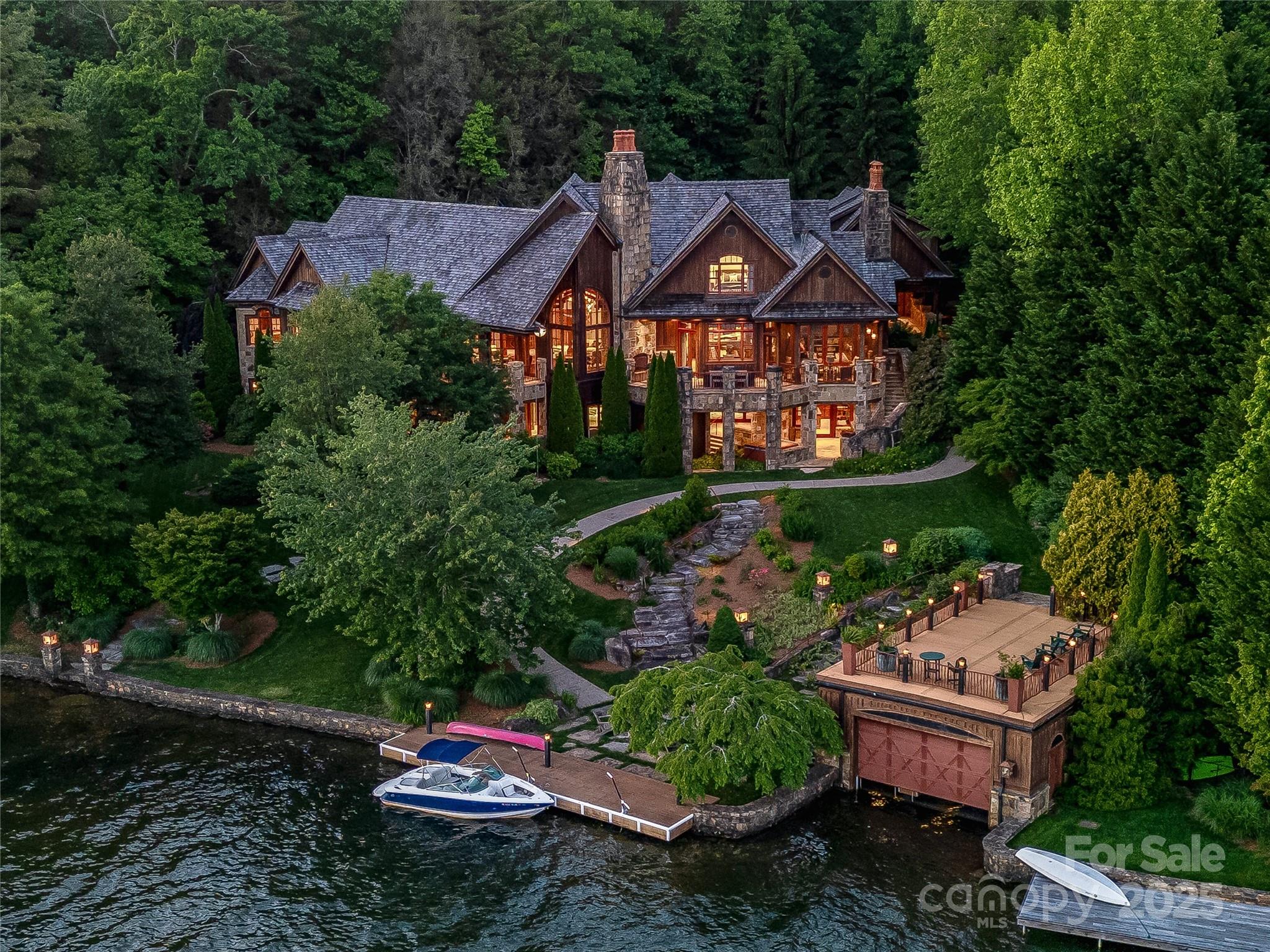 The Mountain Laurel, located at 41 Chimney Point is a premier lakefront estate that epitomizes privacy, exclusive and refined craftsmanship crafted by esteemed builder John Lupoli, the home showcases old world elegance sitting on over 1.3 acres with over 300 feet of Shoreline. The home has too many features to list, but among them include plaster walls, multiple stone fireplaces, an elevator to all floors and expansive outdoor living spaces. The gourmet kitchen is equipped with custom cabinetry, a Lacanche Cote D’Or oven, brass apron and prep sinks and two walk-in pantries. In addition, a covered breezeway connects a double carport, one car garage with a game room, theater, full bath and kitchenette above. This estate offers a serene retreat with breathtaking lake and mountain views, providing an unparalleled living experience in Western North Carolina.