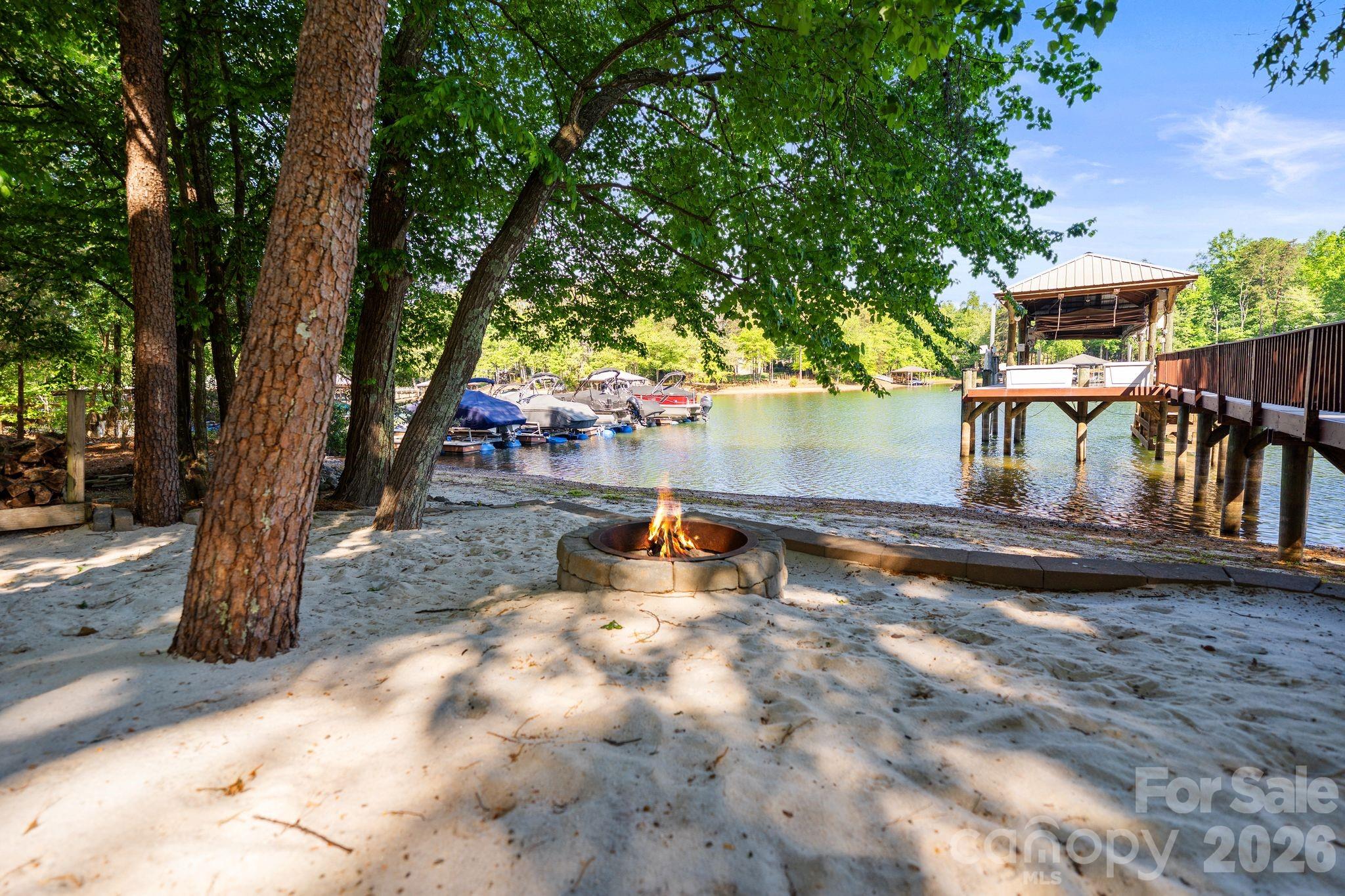 Experience elevated lakefront living in Denver’s premier Sailview community! Situated on an exclusive lot with 76 feet of private shoreline, this exceptional waterfront property features a deep-water pier designed for both convenience and entertainment. The composite-decked dock includes a fixed pier, boat lift, WiFi access, Sonos sound system, motorized automatic touchless boat cover with remote, and remote-powered jet ski lift, everything you need for effortless days on the water. Enjoy your own private sandy beach and firepit, the perfect setting for sunset gatherings by the water. The backyard is a true entertainer’s retreat with a stunning two-level terrace highlighted by a new patio (2019), composite decking, and a dramatic double-sided stone fireplace. Relax year-round in the Bull Frog A9 spa, enjoy two gas heaters for cooler evenings, and take advantage of the outdoor shower after lake days. Additional exterior features include in-ground irrigation pumped directly from the lake, a 10x10 storage shed, landscape lighting, and a tranquil water fountain. The extended private driveway creates an impressive approach to the home while enhancing privacy, and the additional parking pad offers convenient space for extra vehicles, entertaining, or everyday flexibility.  Inside, a soaring 19-foot foyer ceiling makes an unforgettable first impression, with 12-foot ceilings throughout the dining and living rooms enhancing the open, airy feel. Hardwood floors were refinished in 2019 with a rich walnut stain. The kitchen showcases painted cabinetry and island, granite countertops, KitchenAid appliances, and a sunny breakfast nook framed by a wall of windows overlooking the lake. The great room features a gas log fireplace with custom built-ins, while a beautifully appointed sunroom (completed in 2019) offers a floor-to-ceiling stone fireplace topped with a reclaimed wood mantel. The main level also includes a secondary bedroom with full bath and a spacious laundry room with cabinetry and ample storage. Upstairs, the primary suite provides a private retreat alongside two additional bedrooms and an expansive bonus room with built-in desks, custom bench seating, and durable vinyl plank flooring. The finished basement expands the living space with an office or fifth bedroom, full bath, kitchenette, sitting room, recreation area with included pool table, media room, and abundant storage. Residents of Sailview enjoy access to a community pool, pickleball and tennis courts, clubhouse, and year-round social event, offering not just a home, but a lifestyle.